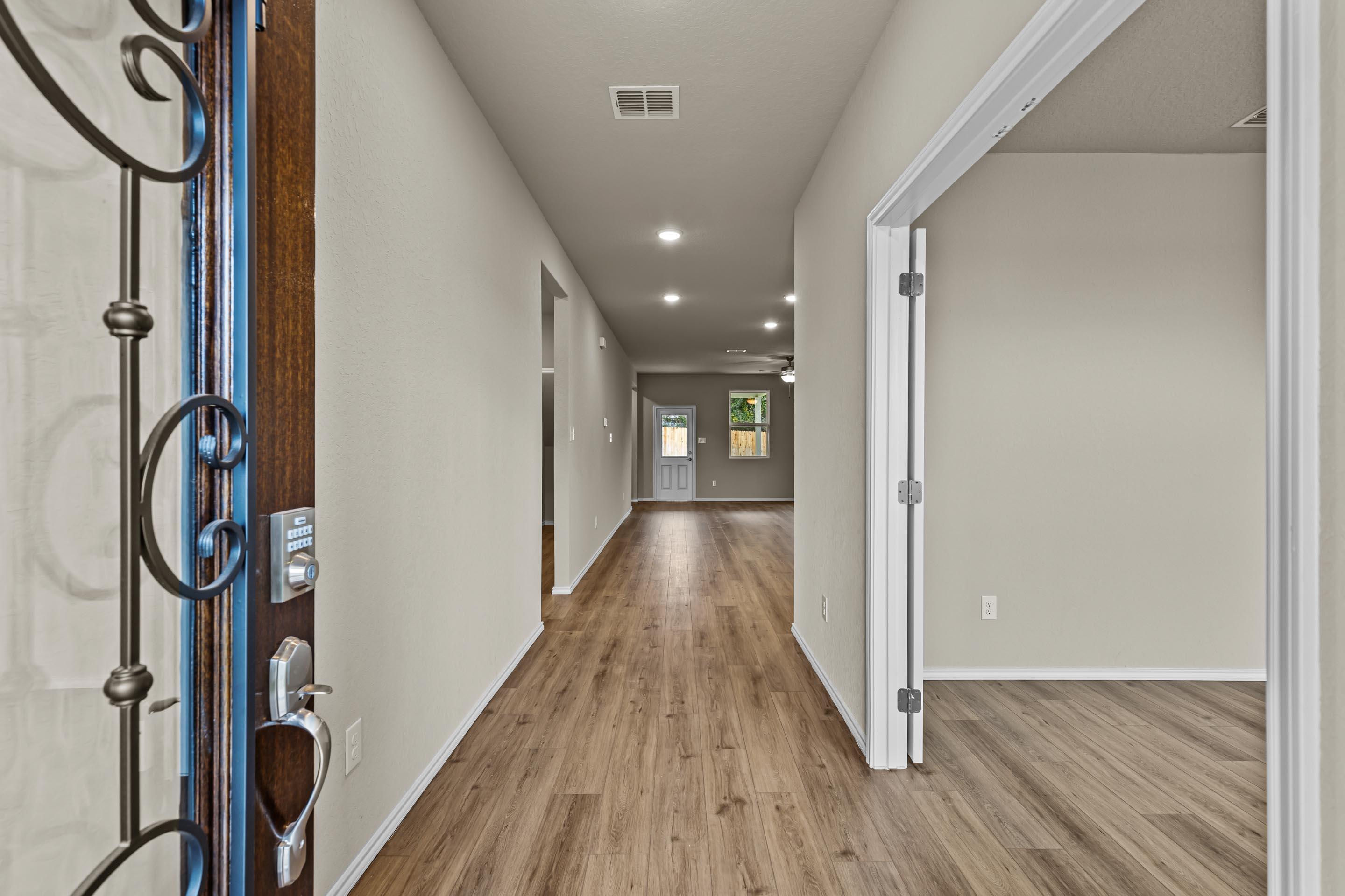 Ornate wooden front door opening to wide hallway with hardwood floors in Davidson Homes The Douglas F, Royal Crest, San Antonio