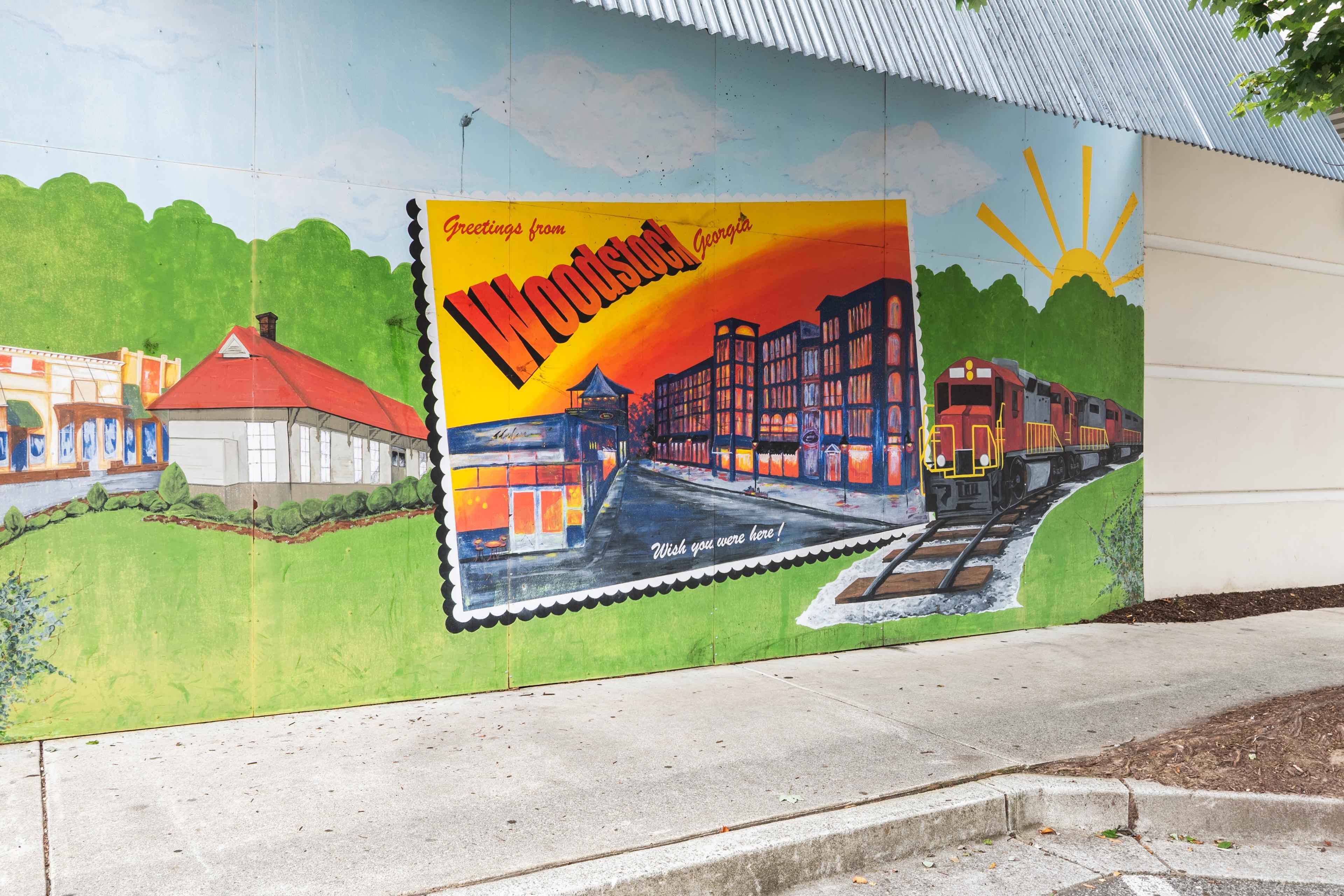 Greetings from Woodstock, Georgia mural depicting local landmarks and a train near the Grafton Trace community.
