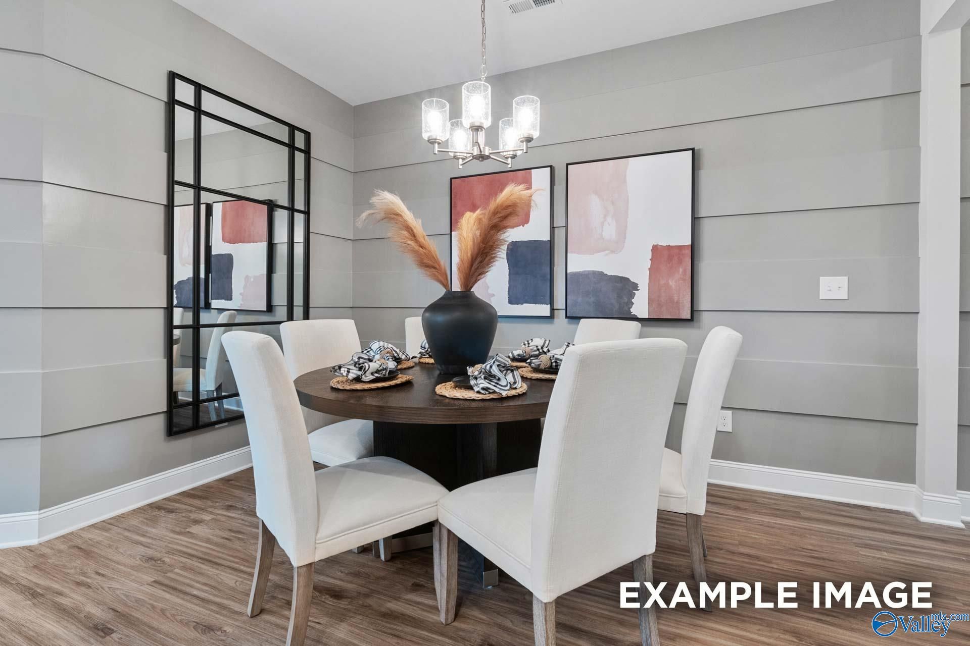 Elegant dining room with round wood table, cream chairs, and modern chandelier in Davidson Homes The Camilla C, Hartselle, Alabama