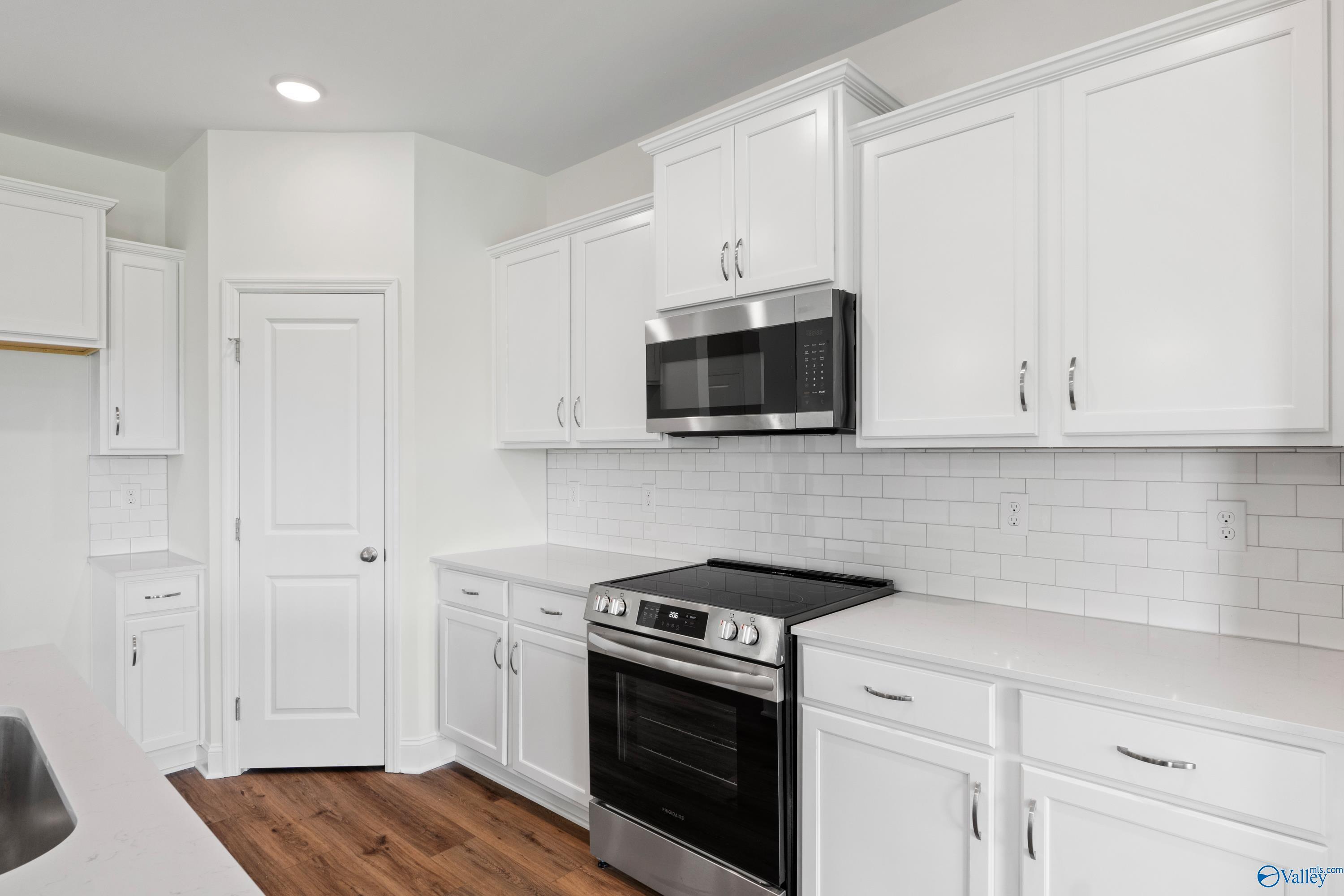 Modern kitchen with white cabinets, subway tile backsplash, and stainless appliances in The Everett B, Athens, Alabama.