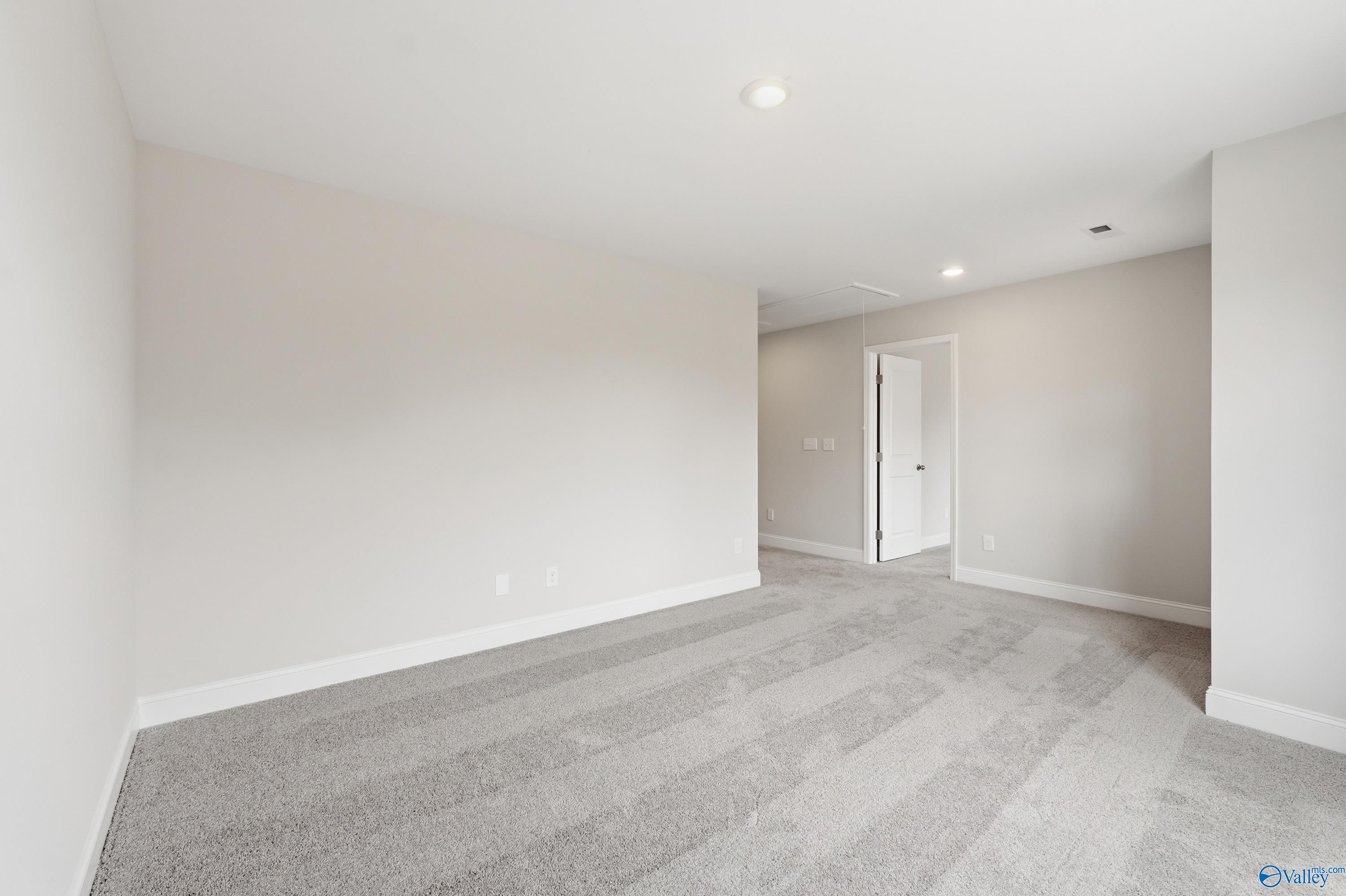 Spacious upstairs hallway with neutral beige walls, gray carpet, and recessed lighting in Davidson Homes The Shelby B, New Market, AL