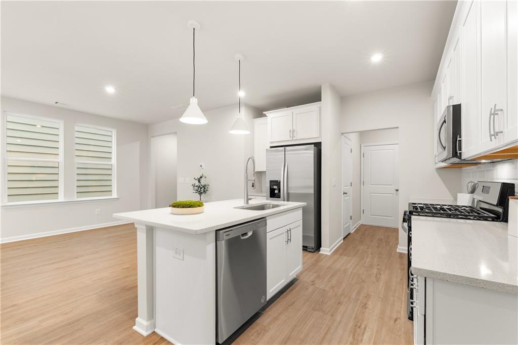 Modern open kitchen with white shaker cabinets, quartz island sink, stainless steel appliances in The Marion B, Kennesaw, GA