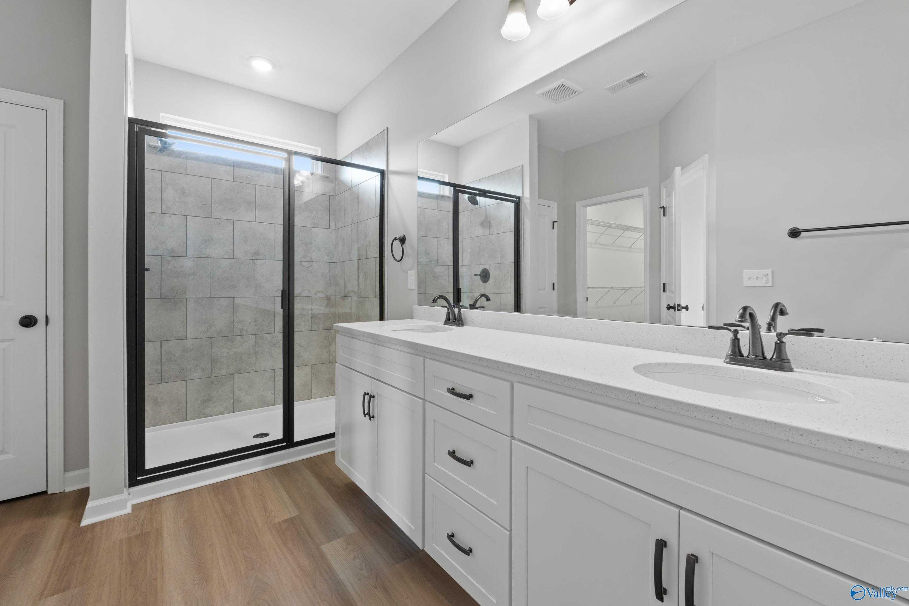 Modern master bathroom with frameless glass shower, double white vanity, and mirrors in Davidson Homes The Dorado, Huntsville, AL