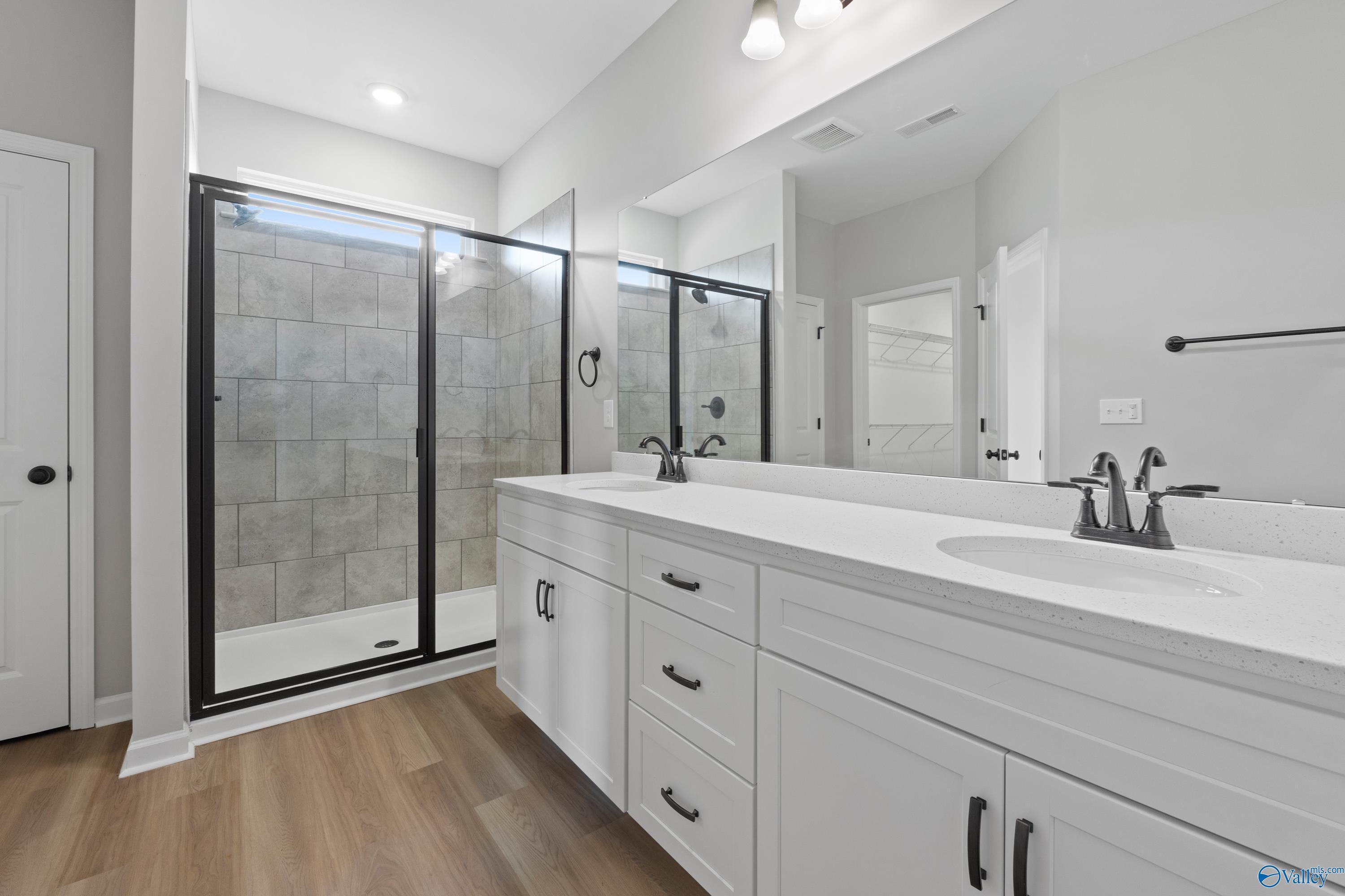 Modern master bathroom with frameless glass shower, double white vanity, and mirrors in Davidson Homes The Dorado, Huntsville, AL