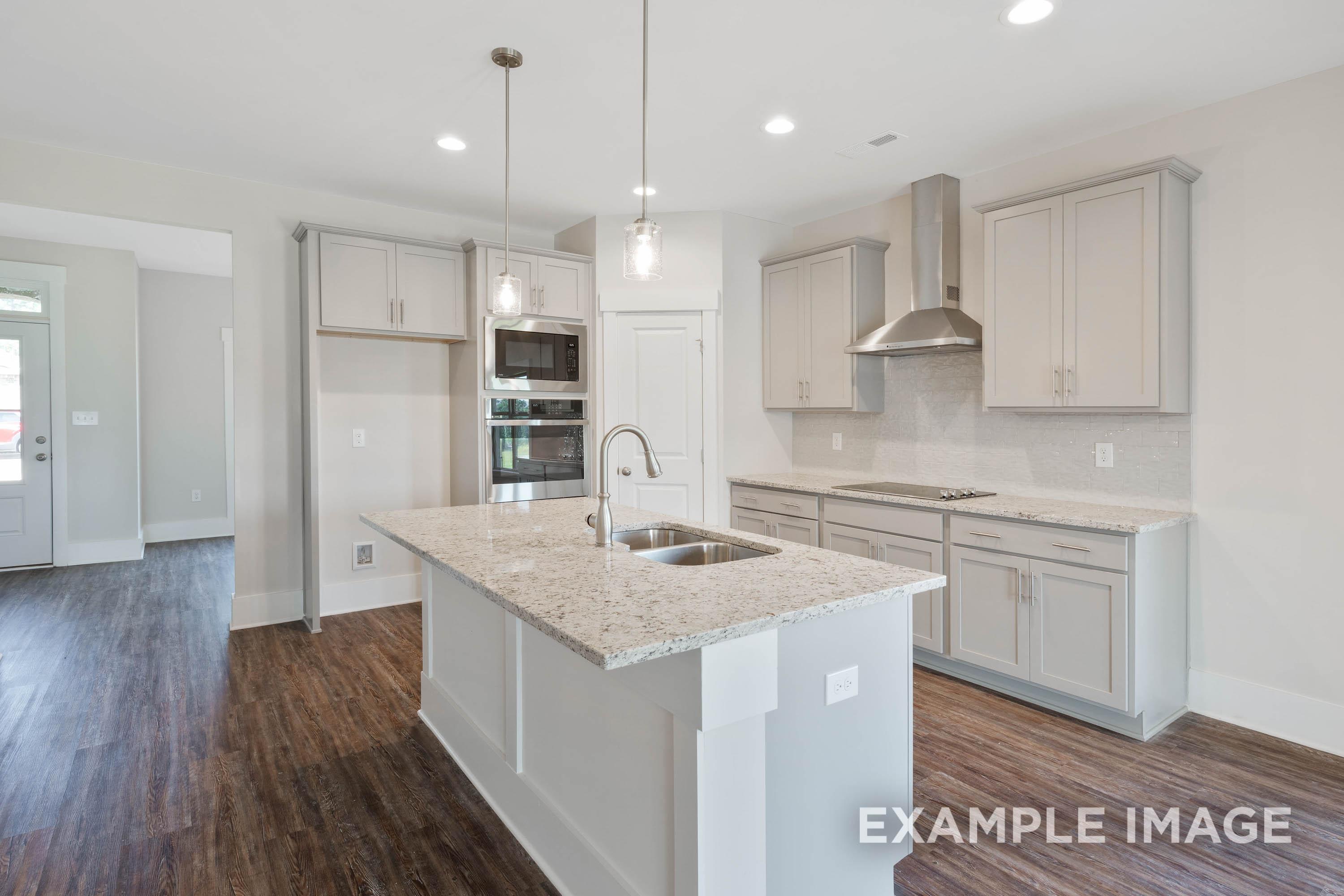 Modern kitchen in The Richmond D featuring a large island, stainless steel appliances, and sleek gray cabinetry.