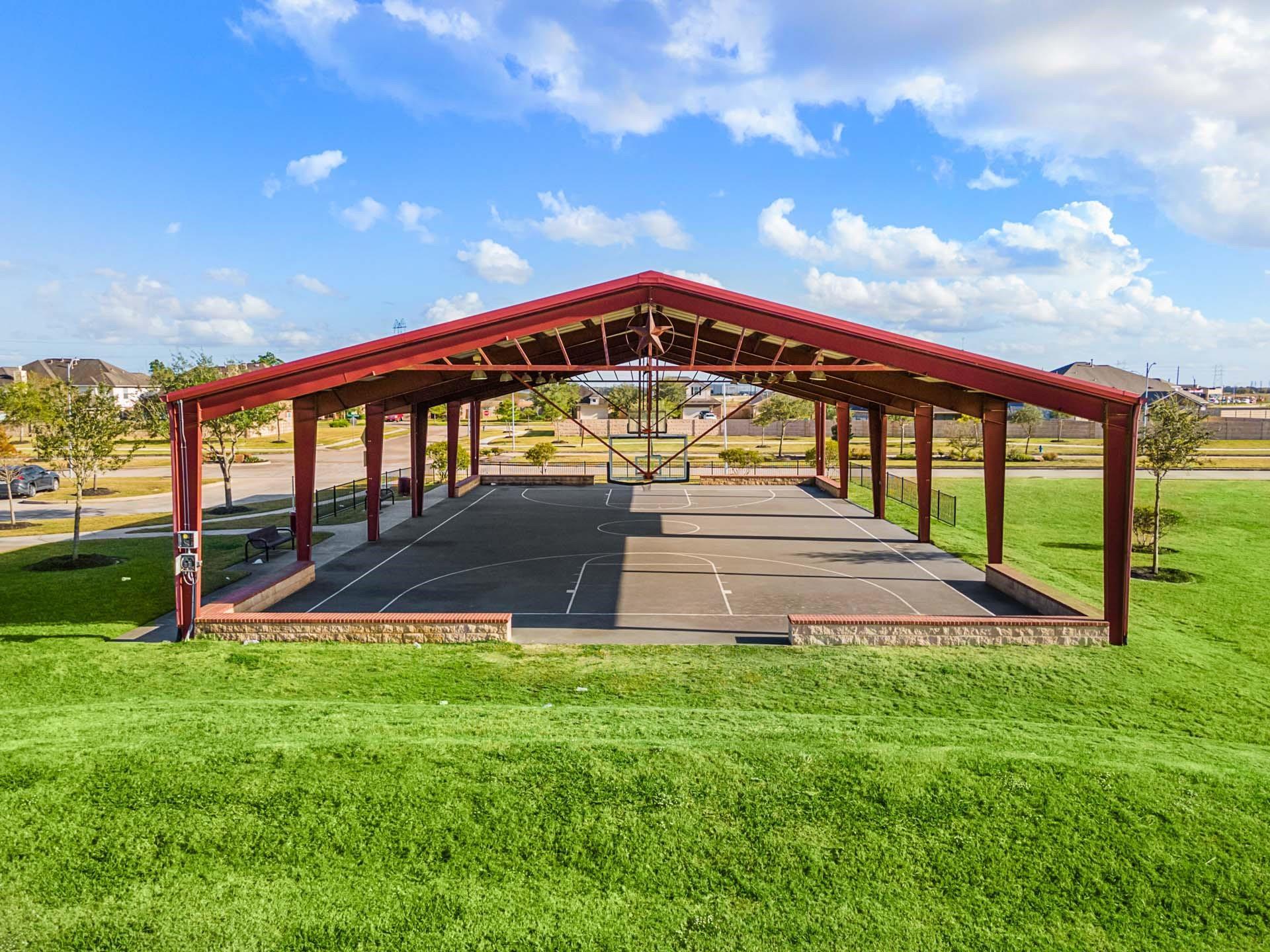 Covered outdoor basketball court with a metal roof at the Sierra Vista community amenities in Rosharon, Texas.