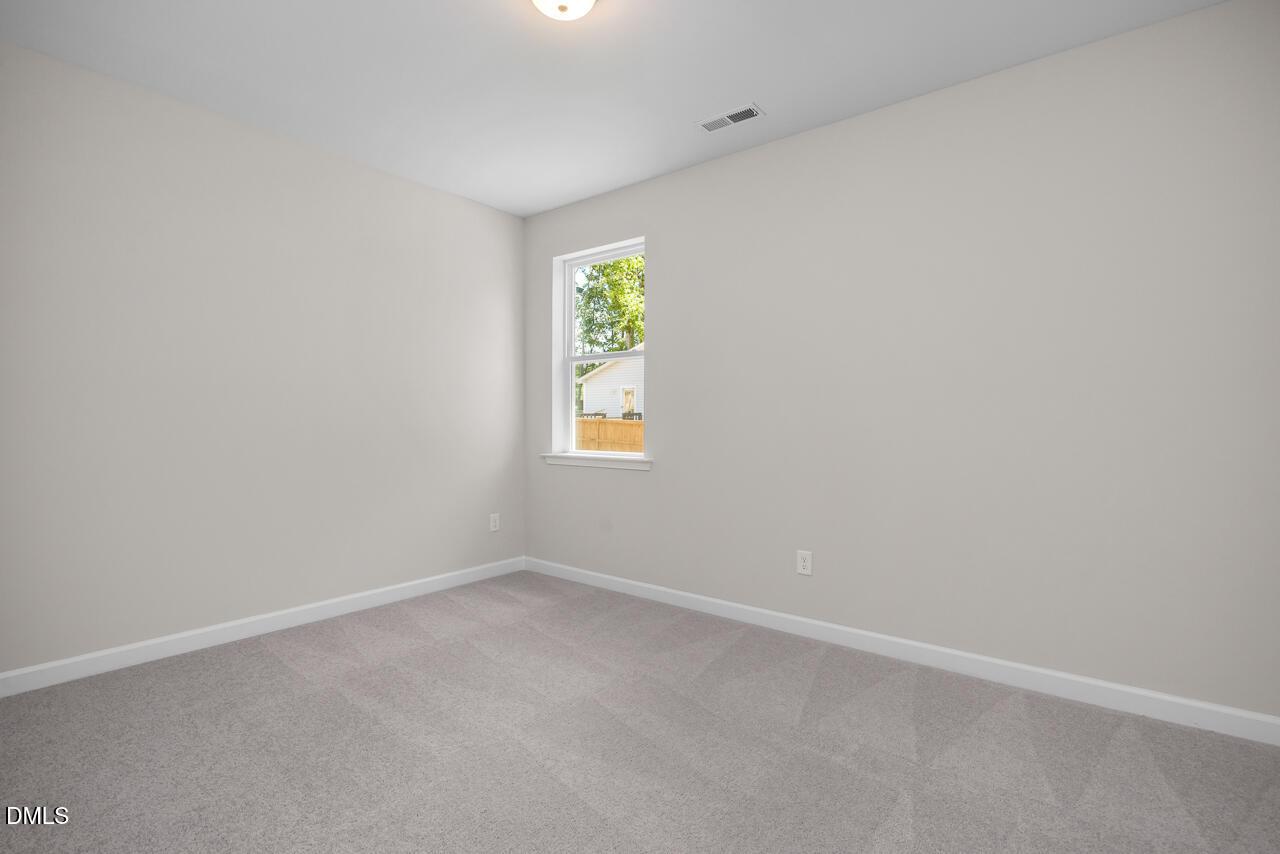 Bright, neutral-toned bedroom with plush carpeting in The Ashport G floor plan at Sage on North Main, Wake Forest, NC.