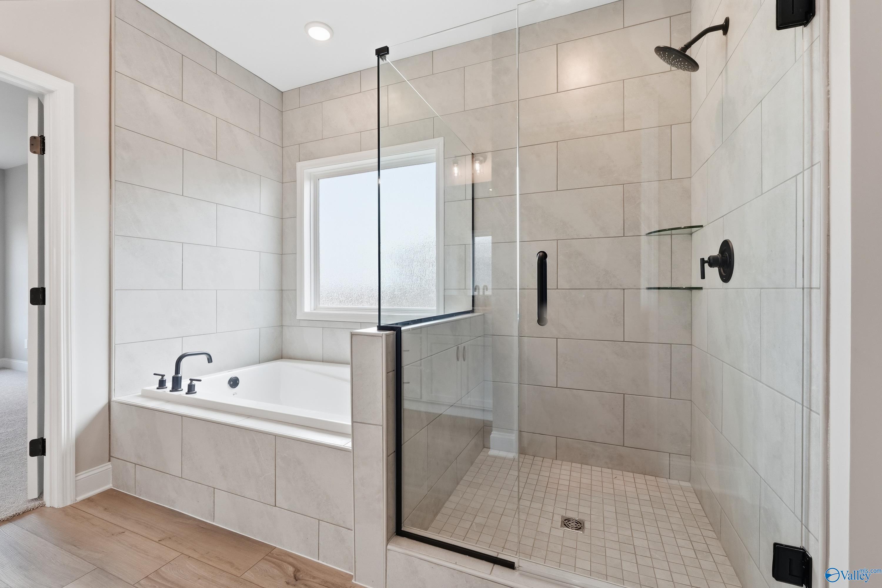 Elegant master bathroom with freestanding tub and glass shower enclosure in Davidson Homes The Rockford C, Athens, Alabama