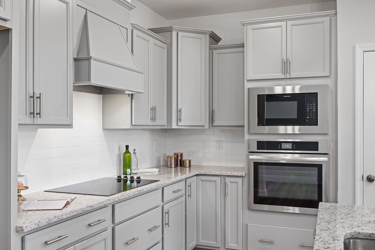 Modern kitchen with light gray cabinets, granite countertops, and stainless steel appliances at Retreat at North Main.