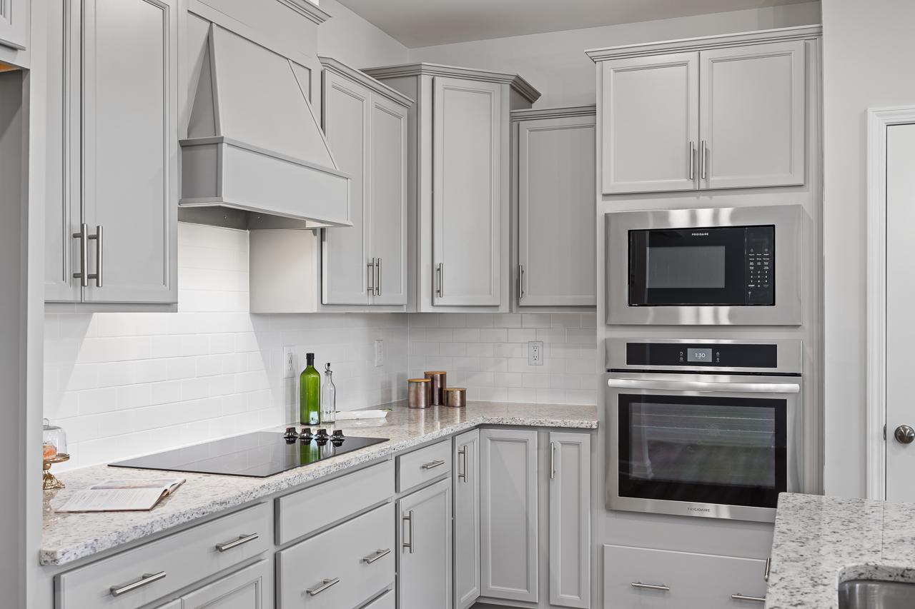 Modern kitchen with light gray cabinets, granite countertops, and stainless steel appliances at Retreat at North Main.