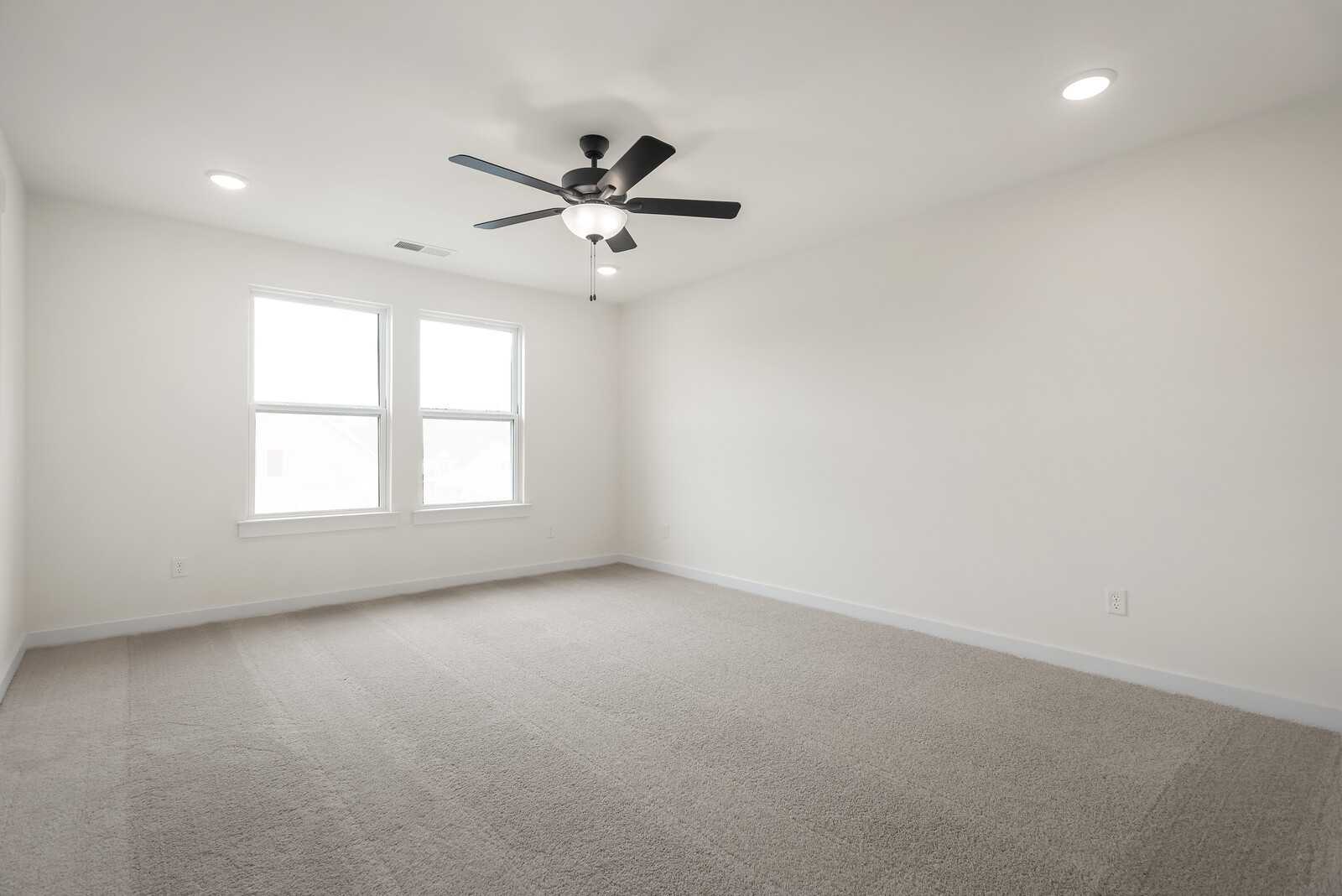 Bright empty secondary bedroom with beige carpet, white walls, double windows, and ceiling fan in Davidson Homes The Logan C, Gallatin, TN