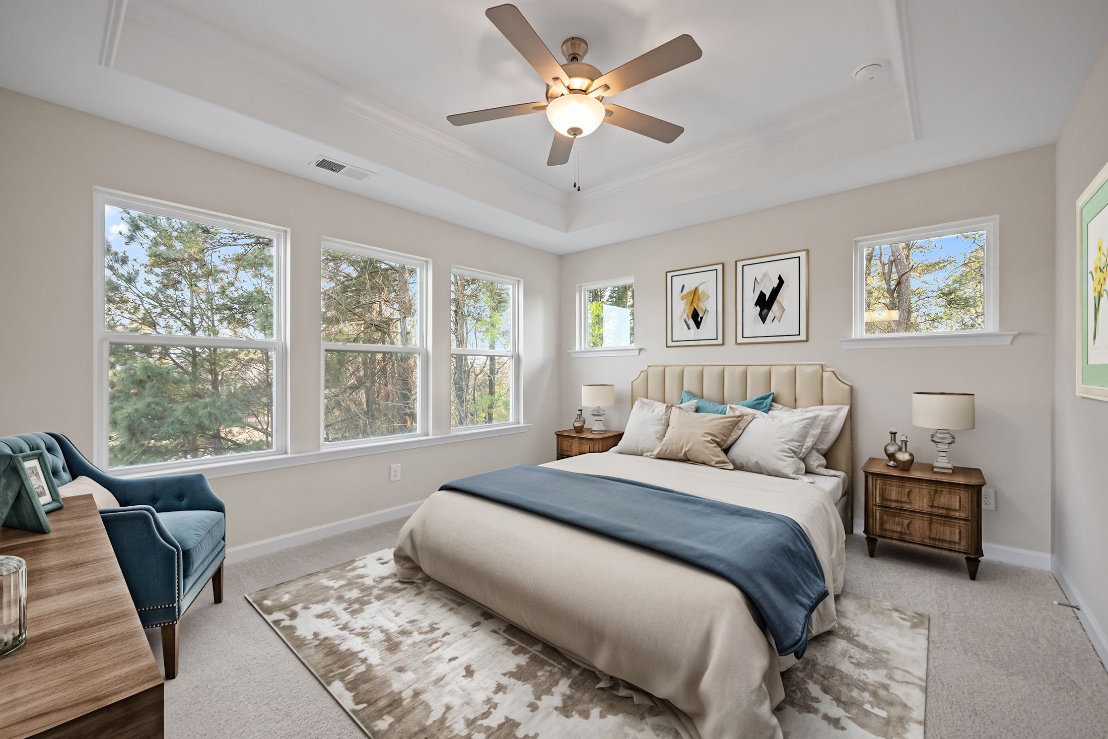 Spacious master bedroom at Forestville Yard Townhomes in Knightdale NC with king bed, large tree-view windows, and blue velvet chair