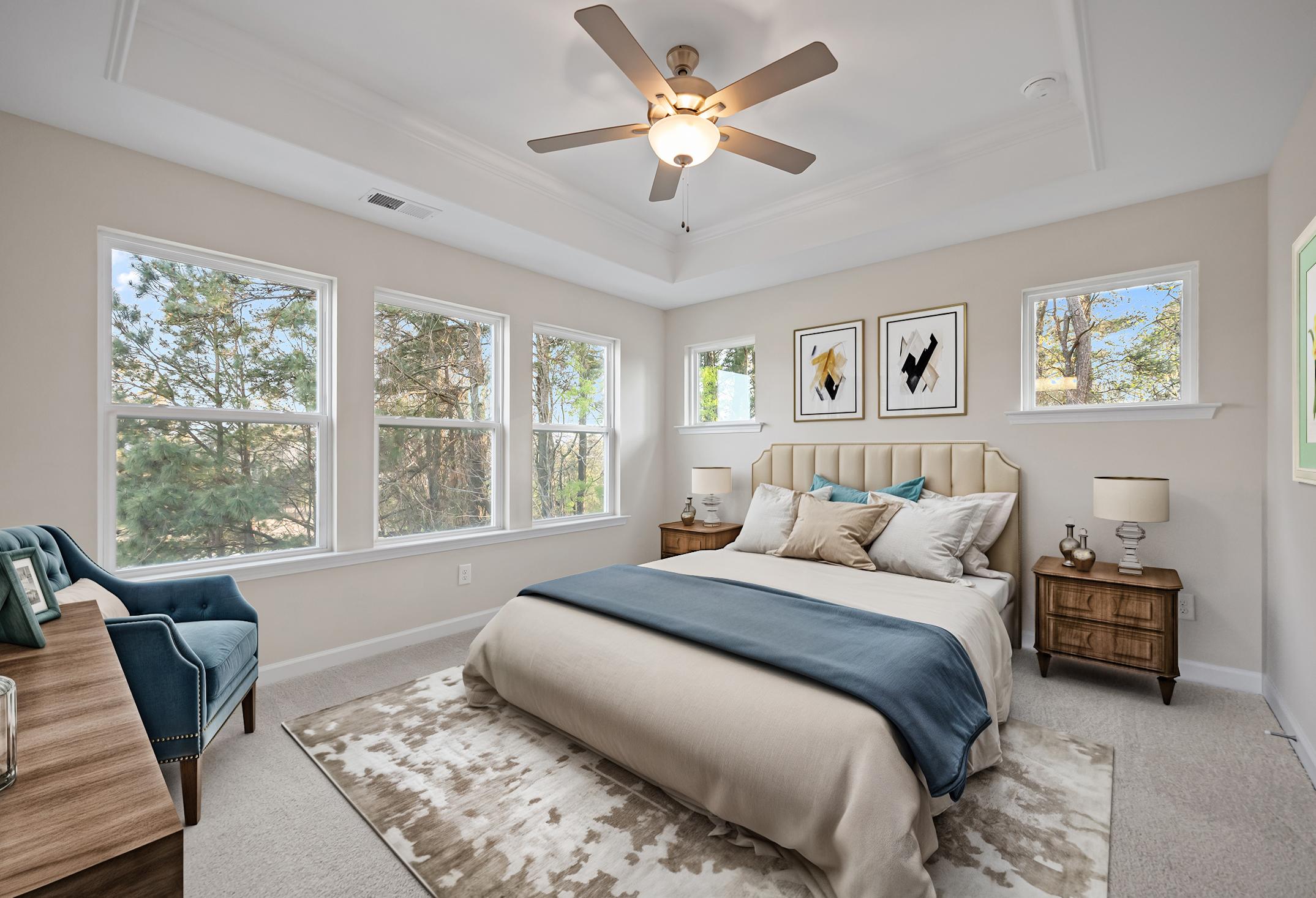 Spacious master bedroom in The Avery featuring a tray ceiling, plush bedding, and natural light in Knightdale, NC.
