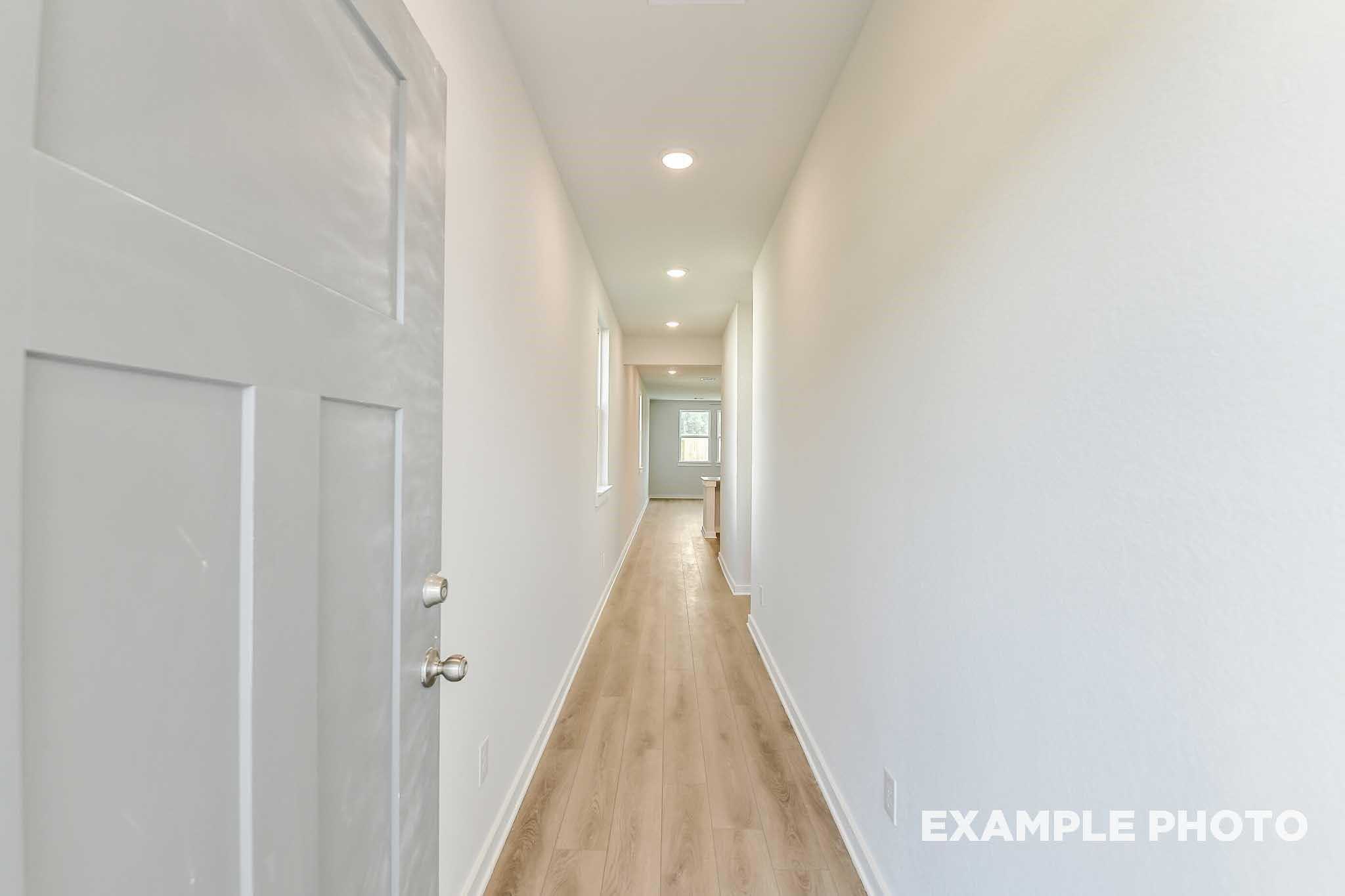 Bright hallway with recessed lighting, white walls, and hardwood floors in Davidson Homes The Colorado F, Conroe, Texas