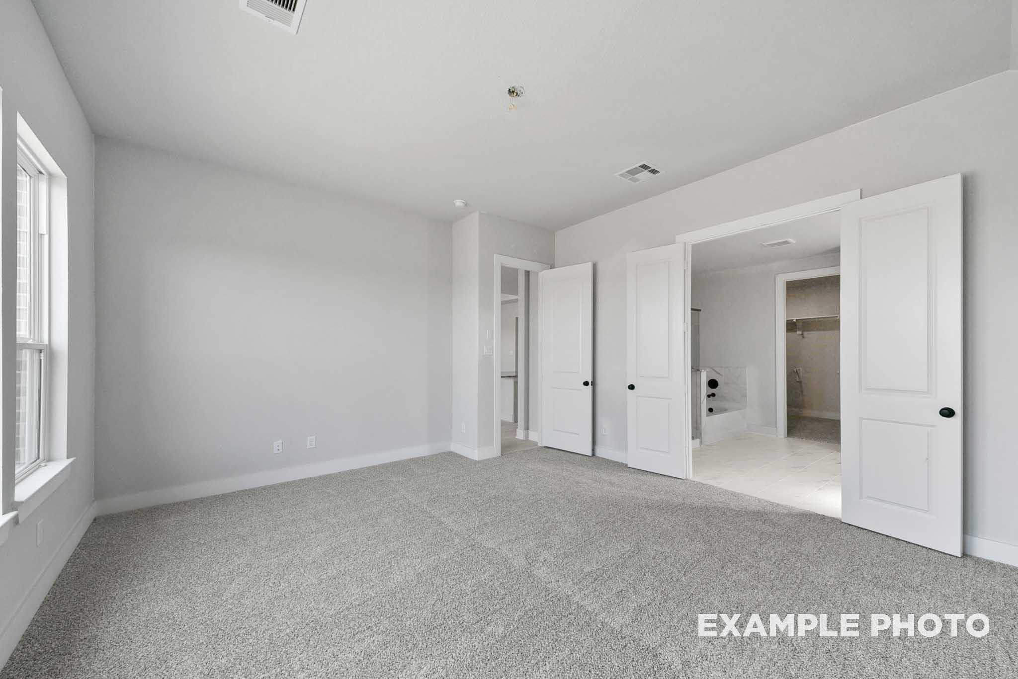 Spacious secondary bedroom with gray walls, carpet flooring, and open doors to bathroom in 5-bedroom Davidson Homes The George A, Lago Mar, Texas City