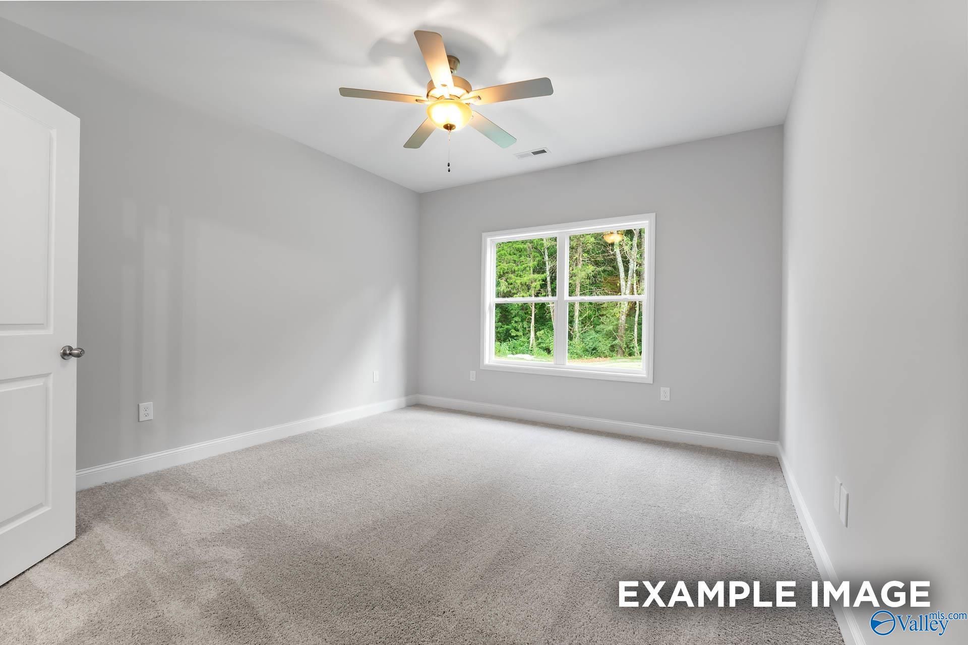 Bright bedroom with ceiling fan, large window overlooking greenery, and gray walls in Davidson Homes The Asheville V, Athens, Alabama