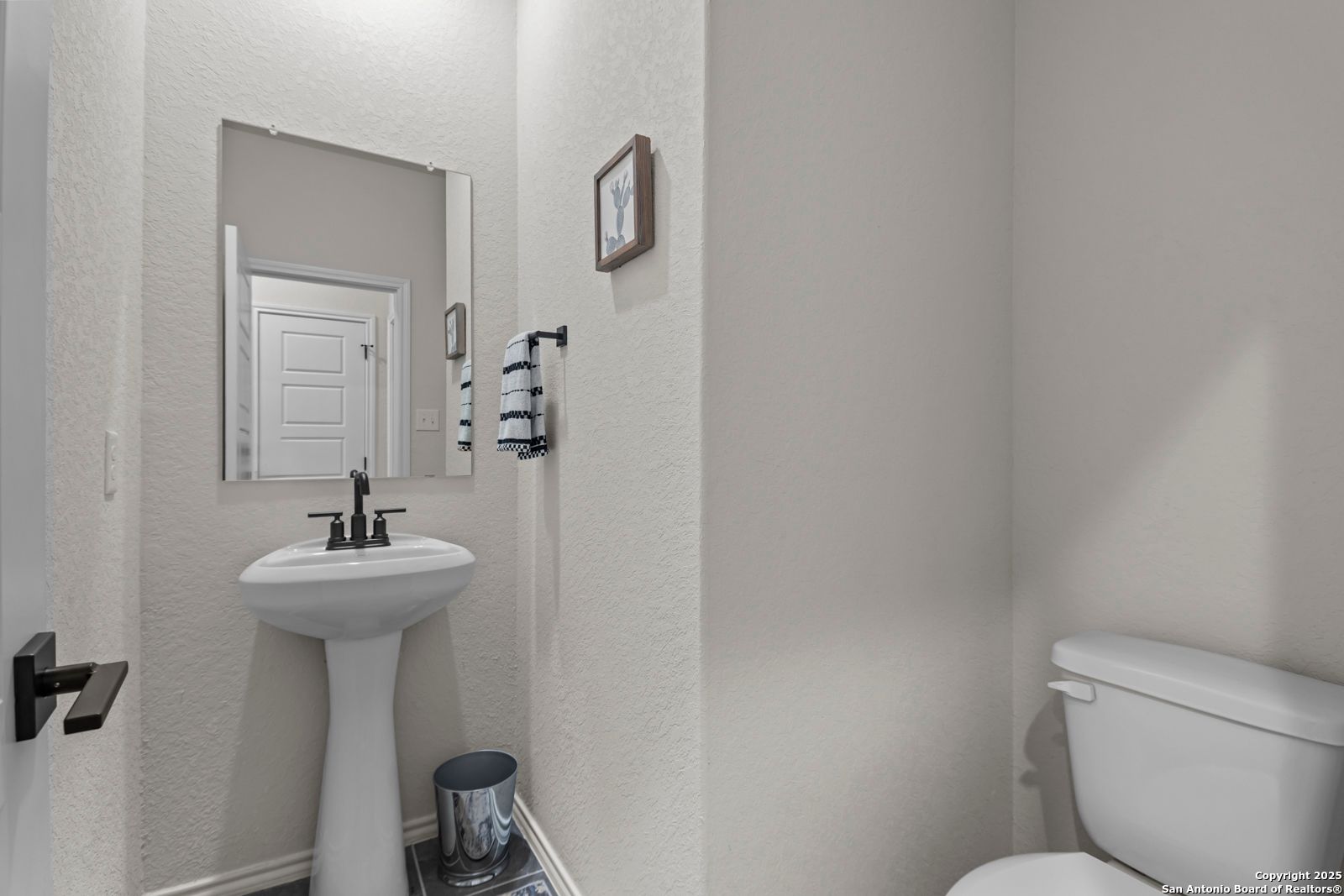 Elegant powder room featuring pedestal sink, framed mirror, and toilet in Davidson Homes The Douglas C, Seguin, Texas