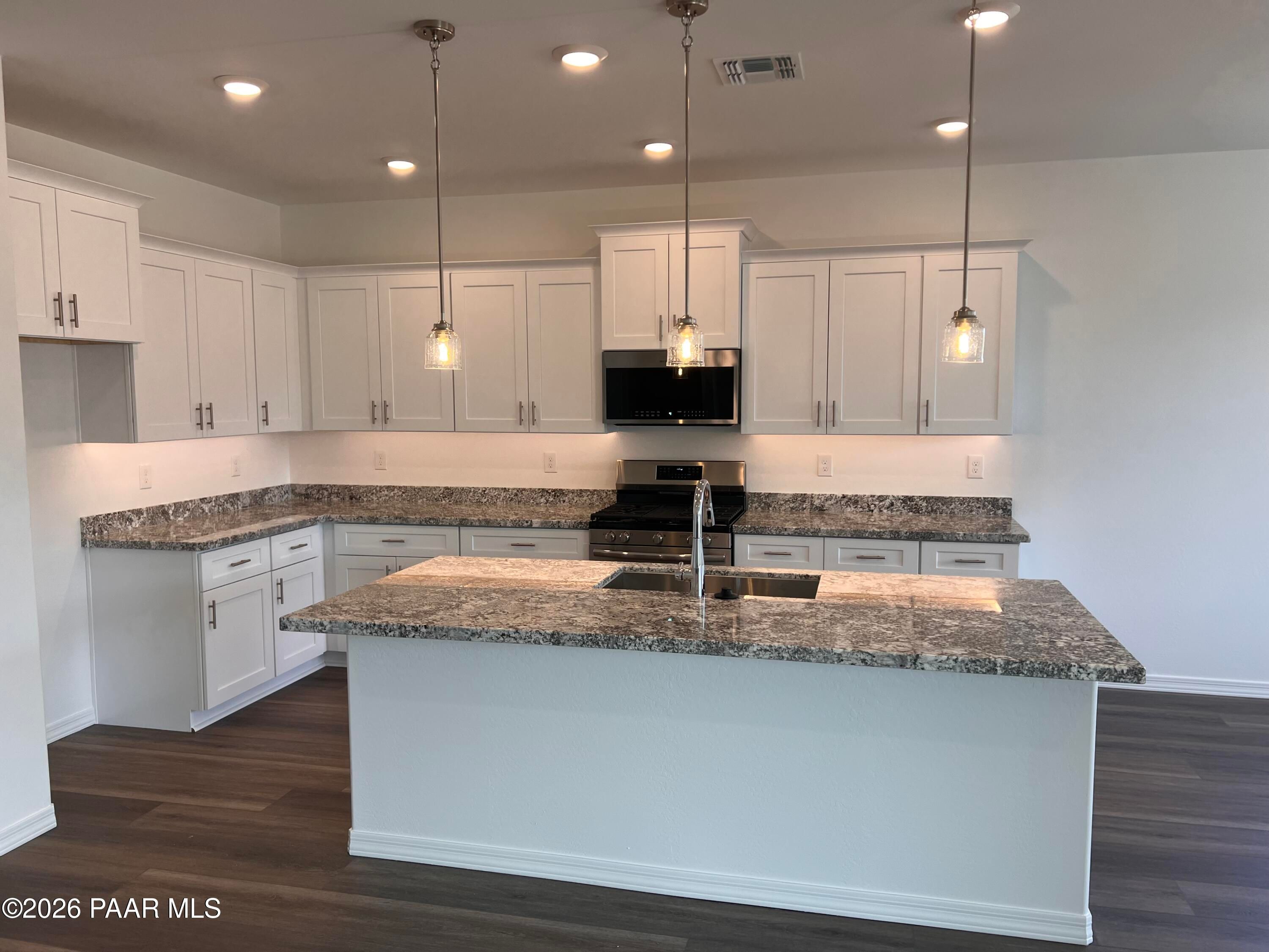 Modern white kitchen with shaker cabinets, quartz island sink, stainless appliances, pendant lights in Davidson Homes The Summit A, Prescott AZ