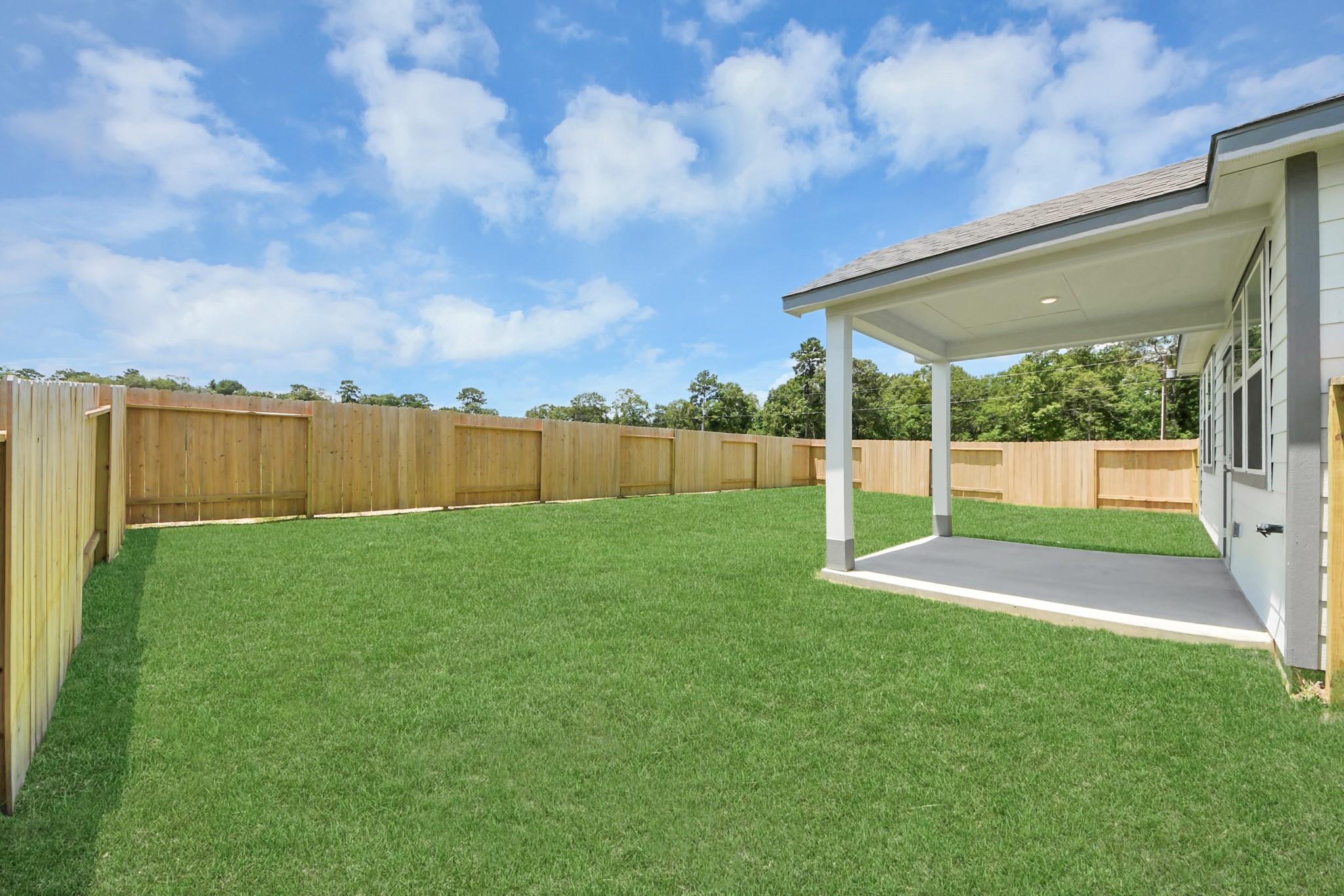 Covered back patio and spacious fenced backyard at The Frio F floor plan in Liberty Estates, Cleveland, Texas.