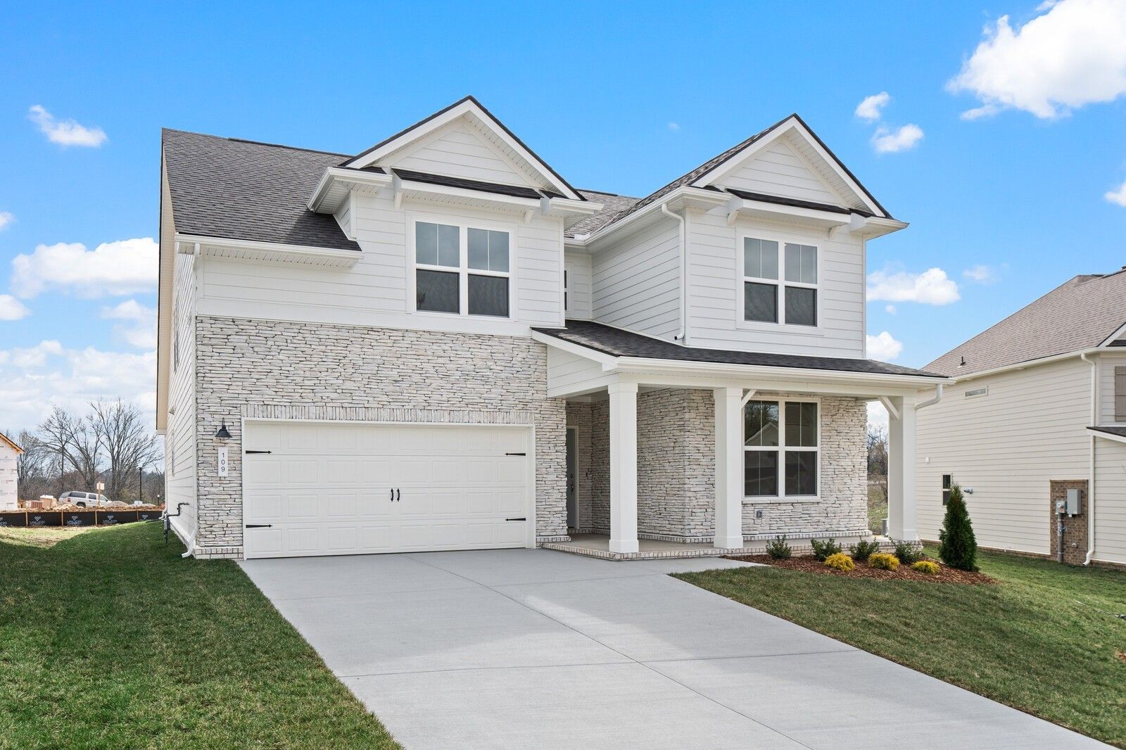 Modern two-story Ridgeport home by Davidson Homes: white brick exterior, covered porch, 2-car garage in Woods Crossing, Gallatin, TN