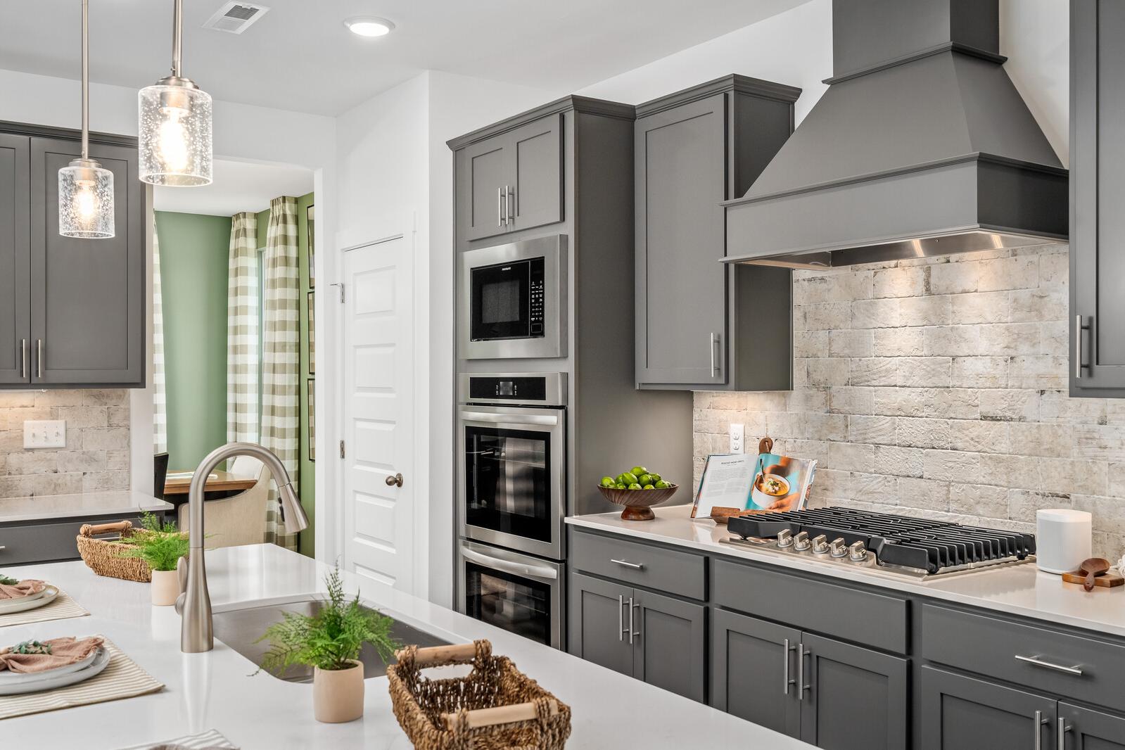 Modern kitchen with gray shaker cabinets, white quartz island, gas range, and subway tile backsplash at Calista Farms, White House TN