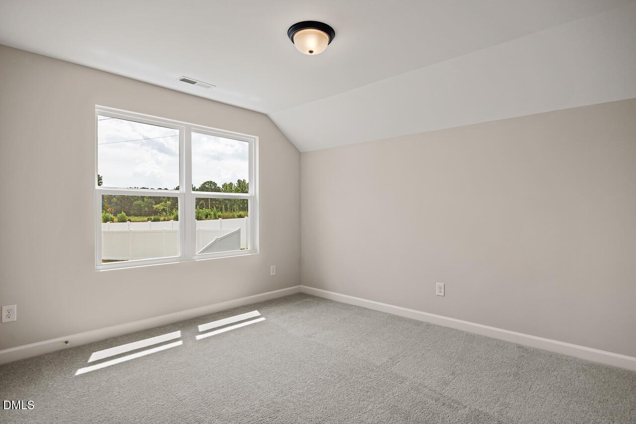 Bright, carpeted bedroom with neutral walls and large windows in The Ash C floor plan at Woodland Crossing, Zebulon, NC.