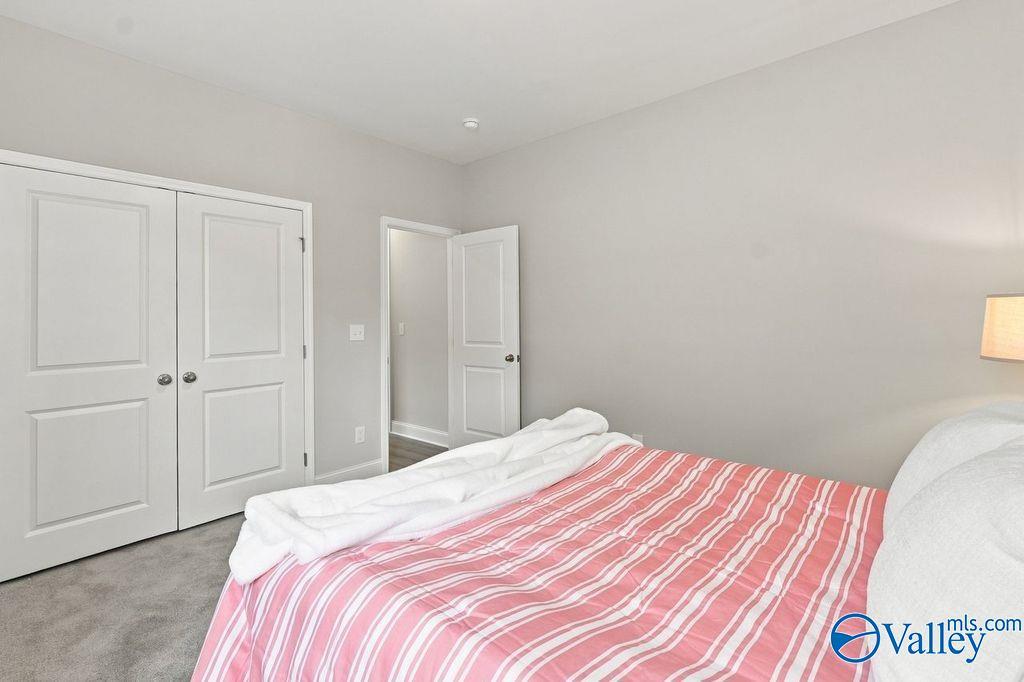 Bright bedroom with striped bedding and dual-door closet in The Harrison floor plan by Davidson Homes, Hartselle, Alabama