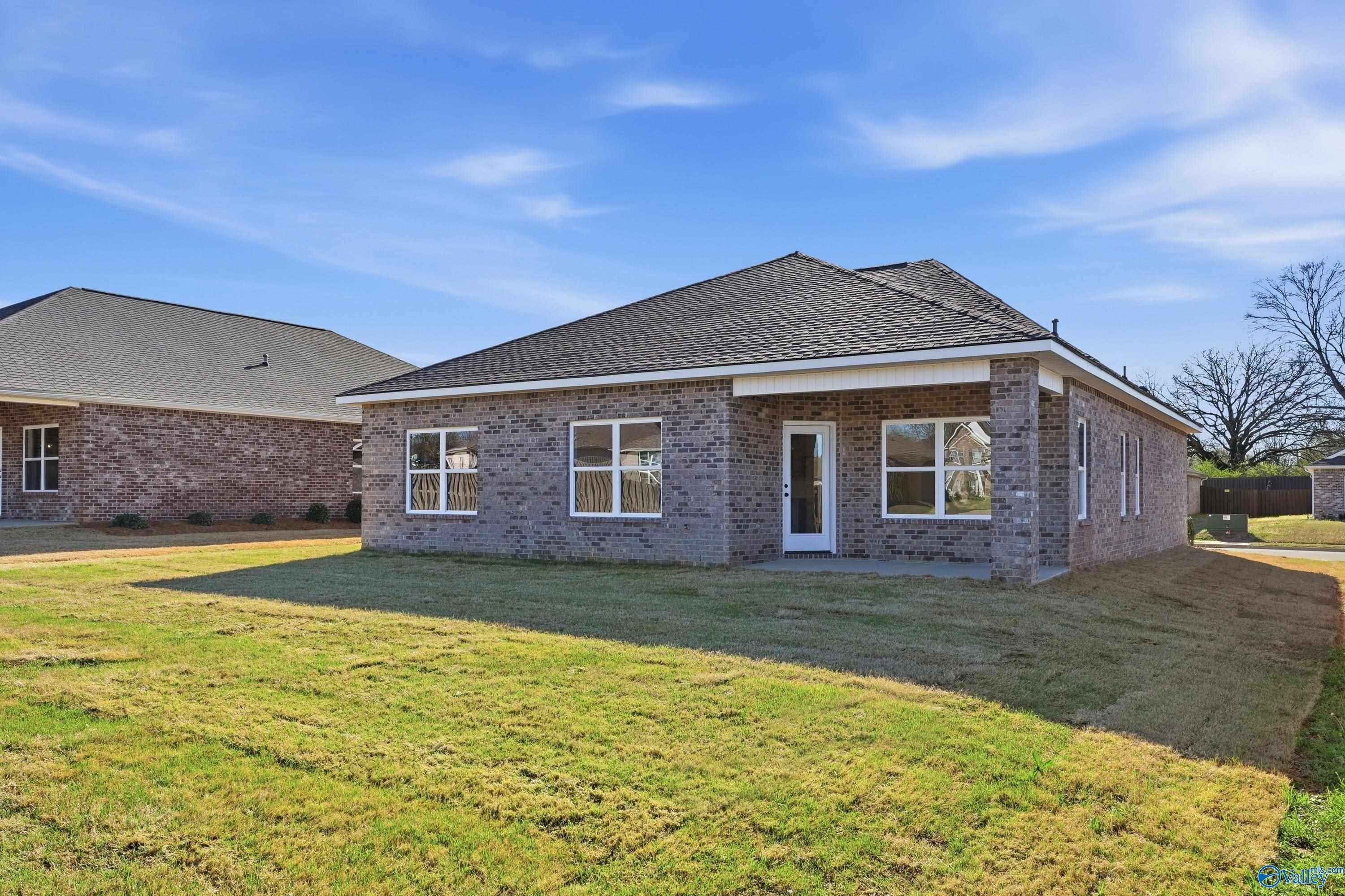 Single-story brick home with gabled roof, white-trimmed windows, and covered porch on green lawn in Flint Meadows, New Market, Alabama