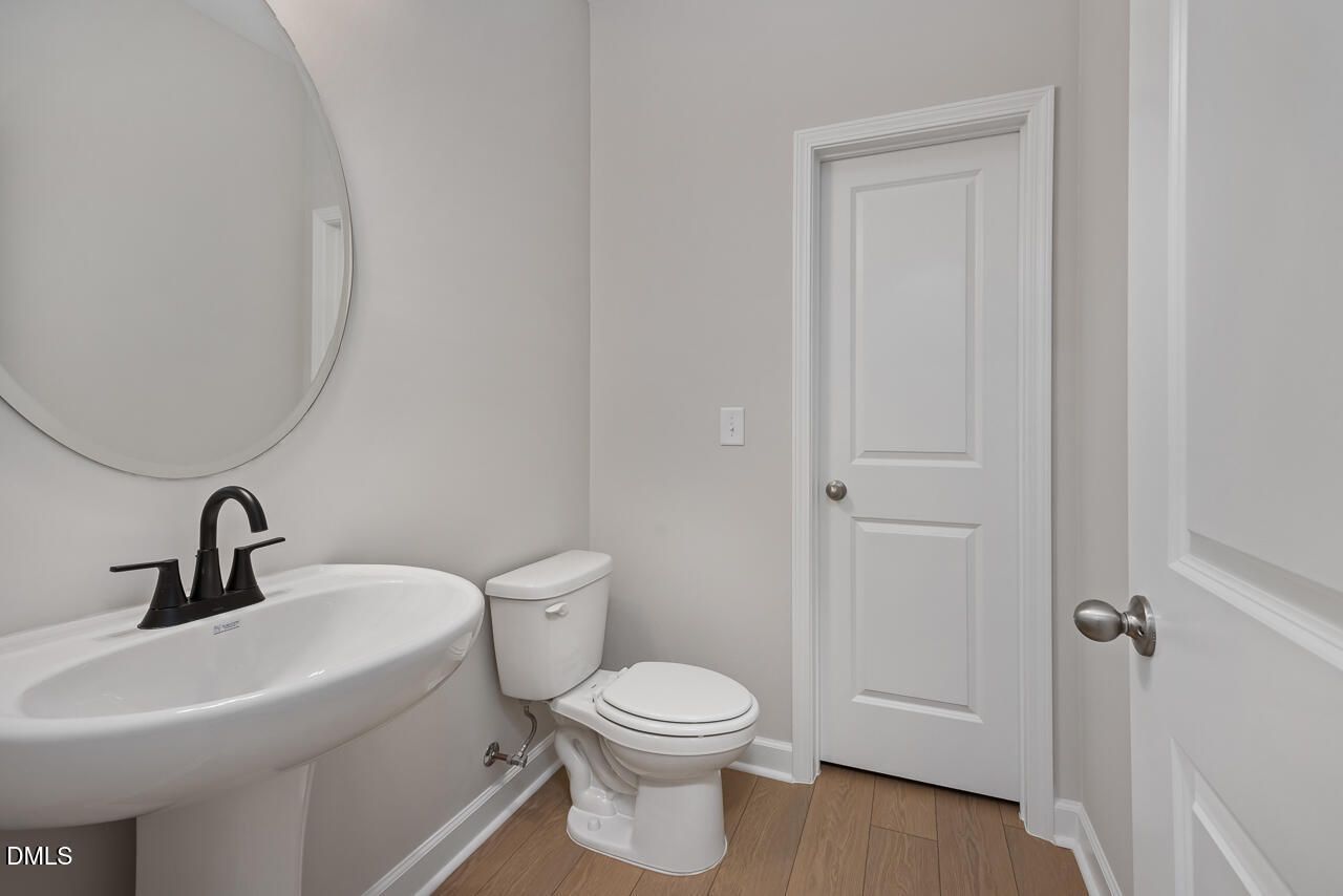 Modern powder room with pedestal sink, matte black faucet, and oval mirror in The Ashport L at Sage on North Main.