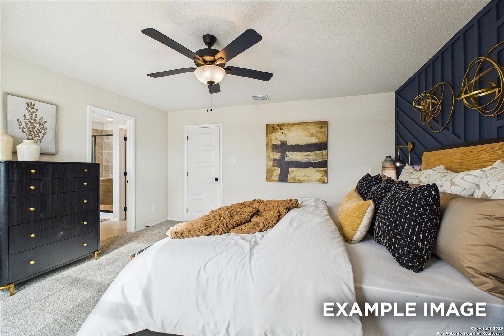 Elegant master bedroom with navy accent wall, gold geometric decor, plush king bed, and en-suite in Davidson Homes The Florence C, San Antonio