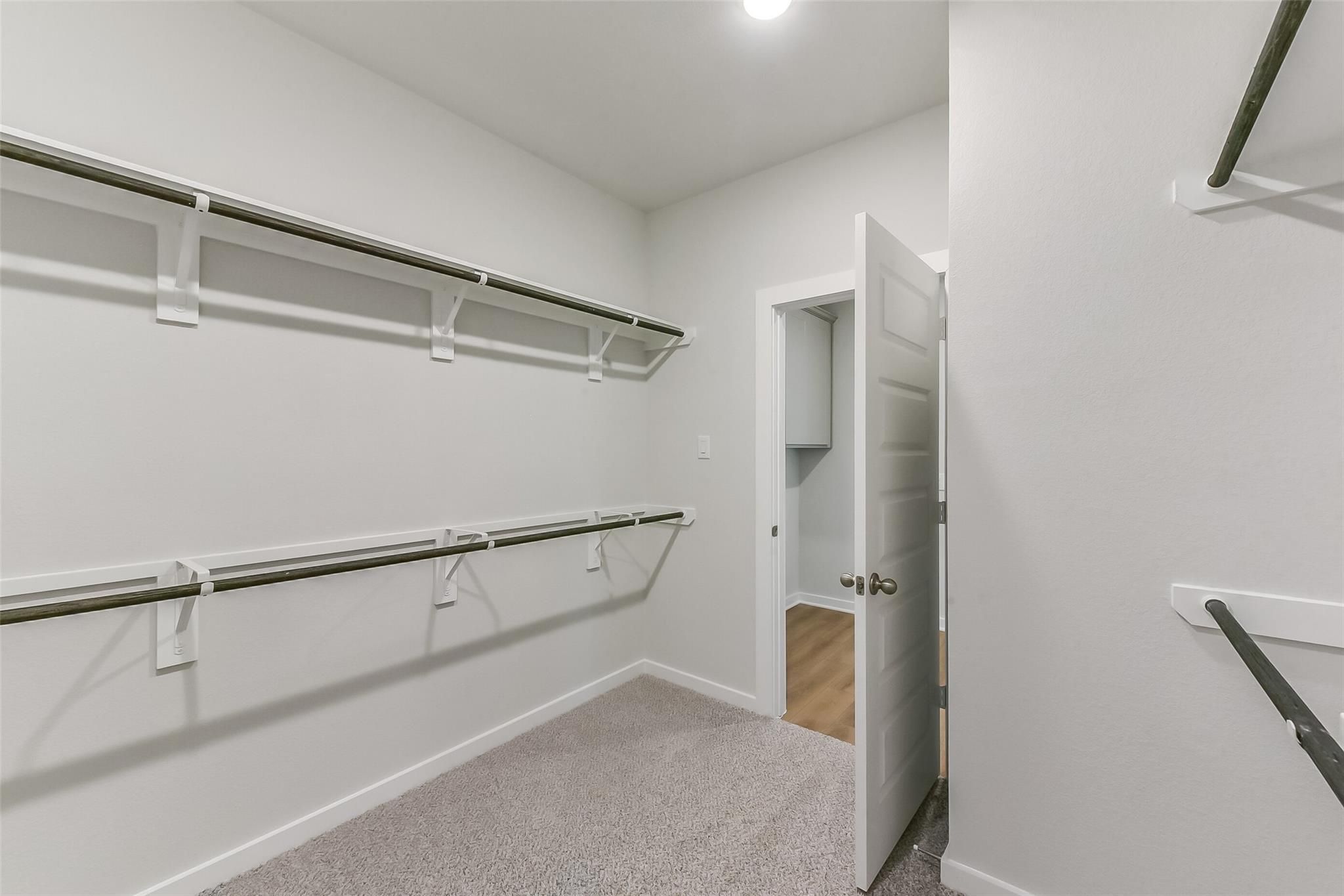 Spacious walk-in closet with custom metal rods and shelving in Davidson Homes The Tierra C master suite, Dayton TX