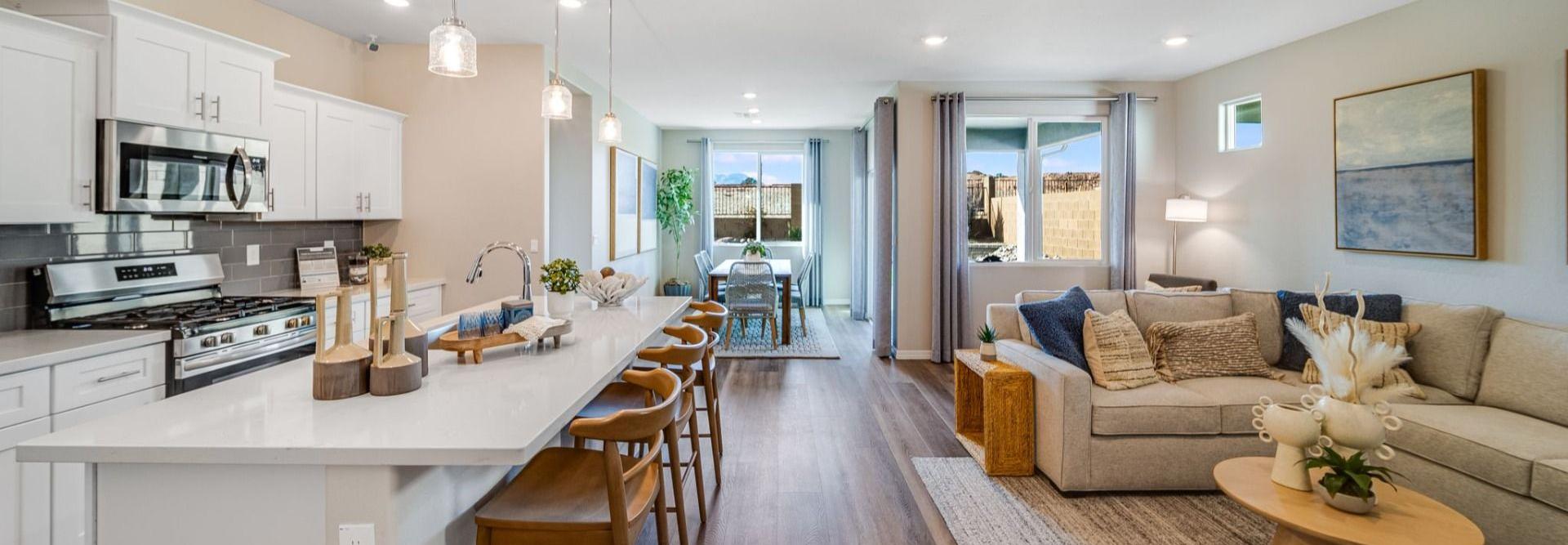 Open-concept kitchen and living room in South Ranch Prescott AZ home with white island, hardwood floors, and neutral sofa seating