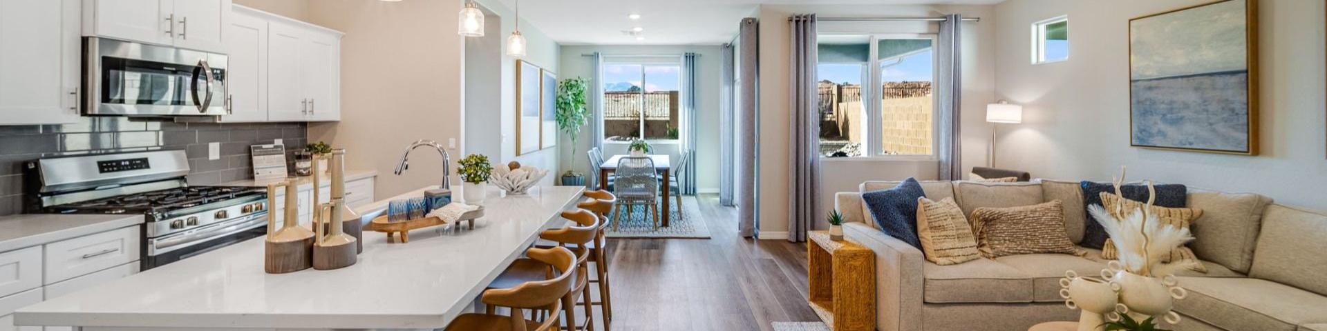 Open-concept kitchen and living room in South Ranch Prescott AZ home with white island, hardwood floors, and neutral sofa seating