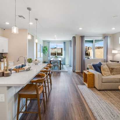 Open-concept kitchen and living room in South Ranch Prescott AZ home with white island, hardwood floors, and neutral sofa seating