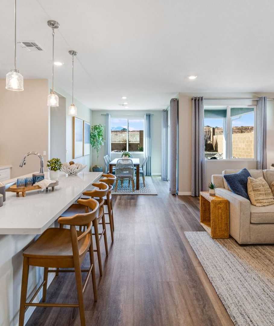 Open-concept kitchen and living room in South Ranch Prescott AZ home with white island, hardwood floors, and neutral sofa seating