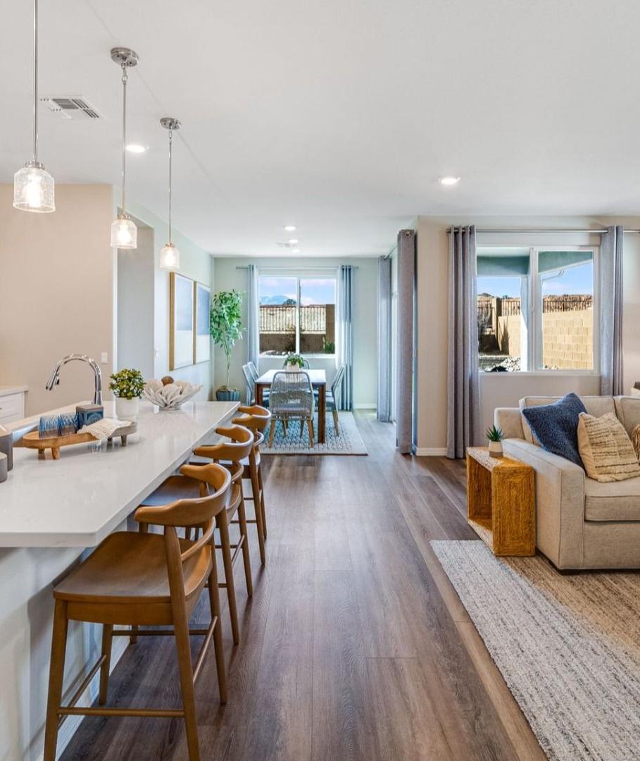 Open-concept kitchen and living room in South Ranch Prescott AZ home with white island, hardwood floors, and neutral sofa seating