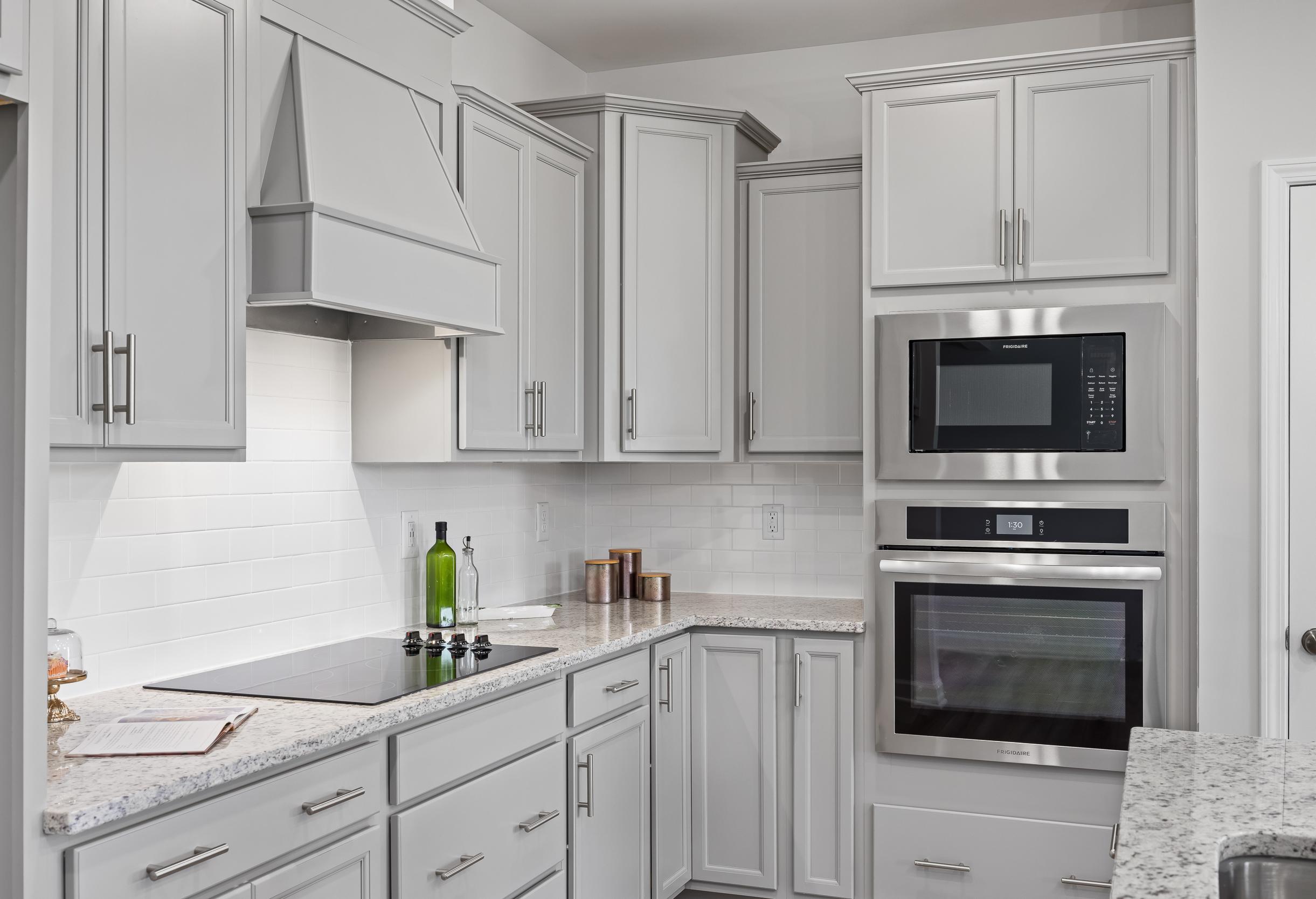 Spacious kitchen in The Daphne C featuring white shaker cabinets, stainless steel double oven, induction cooktop, and quartz counters