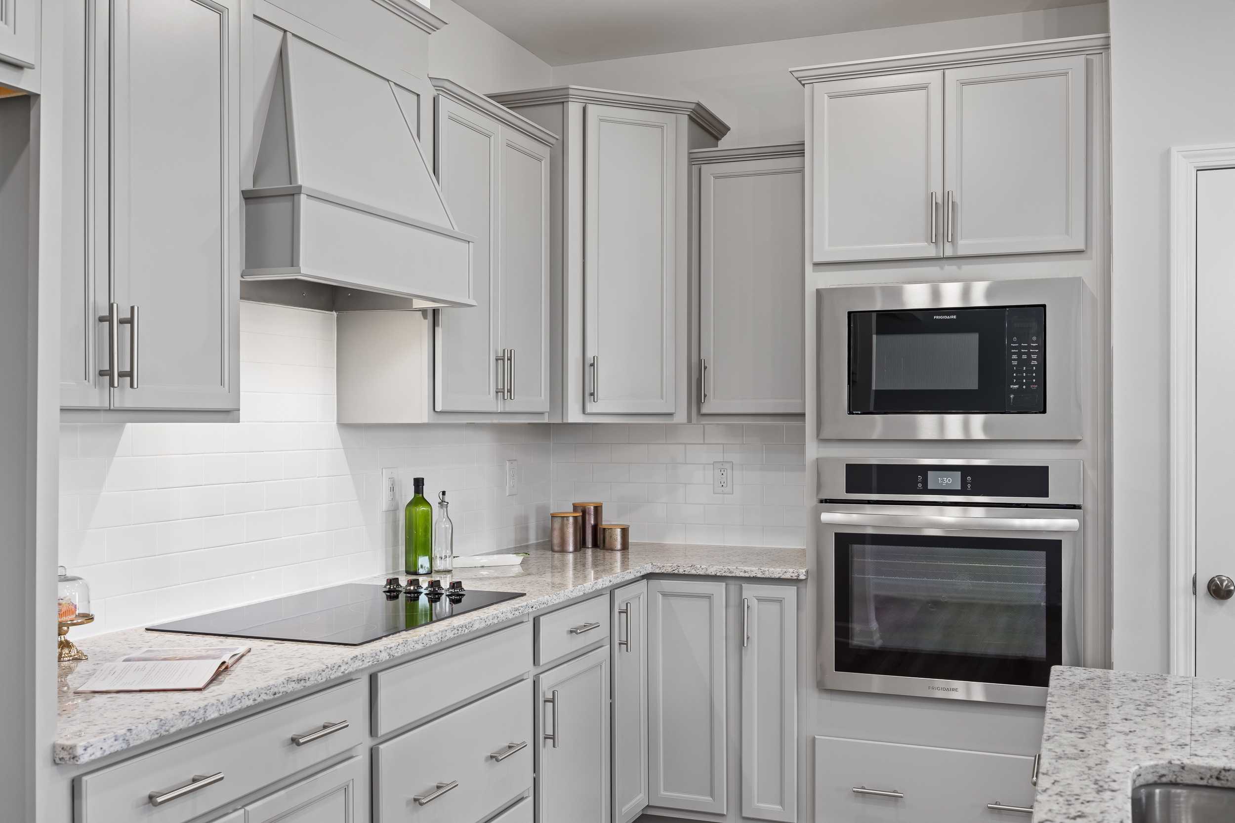 Spacious kitchen in The Daphne C featuring white shaker cabinets, stainless steel double oven, induction cooktop, and quartz counters