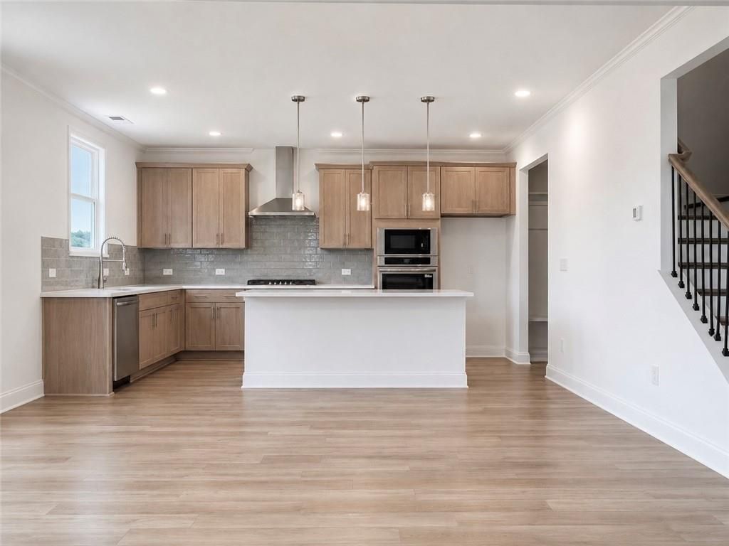 Modern kitchen with wood cabinets, center island, and stainless appliances in The Hickory C floor plan, Wehunt Meadows.