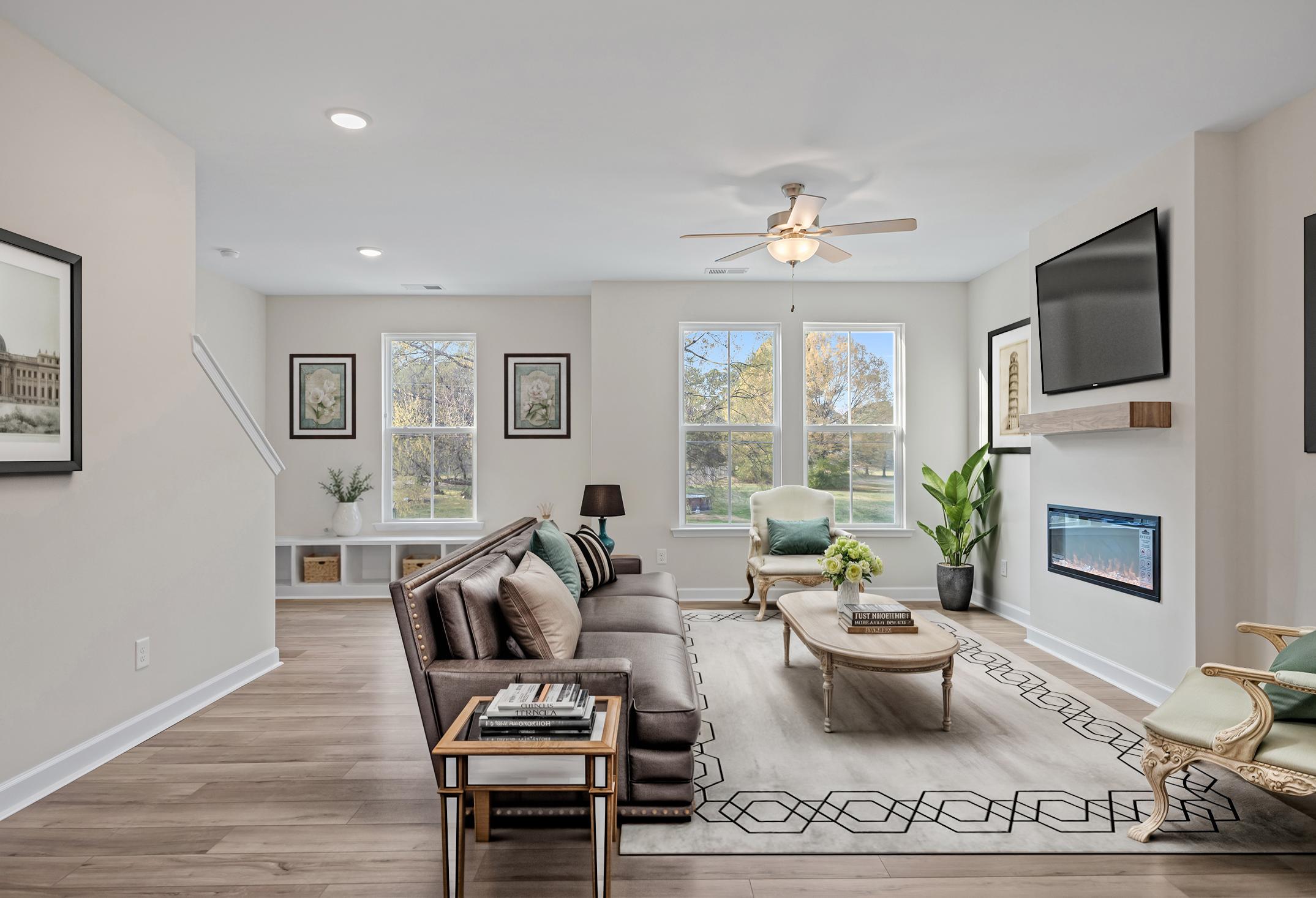 Spacious open-concept living area in The Avery featuring a modern fireplace, stylish furniture, and hardwood-style flooring.