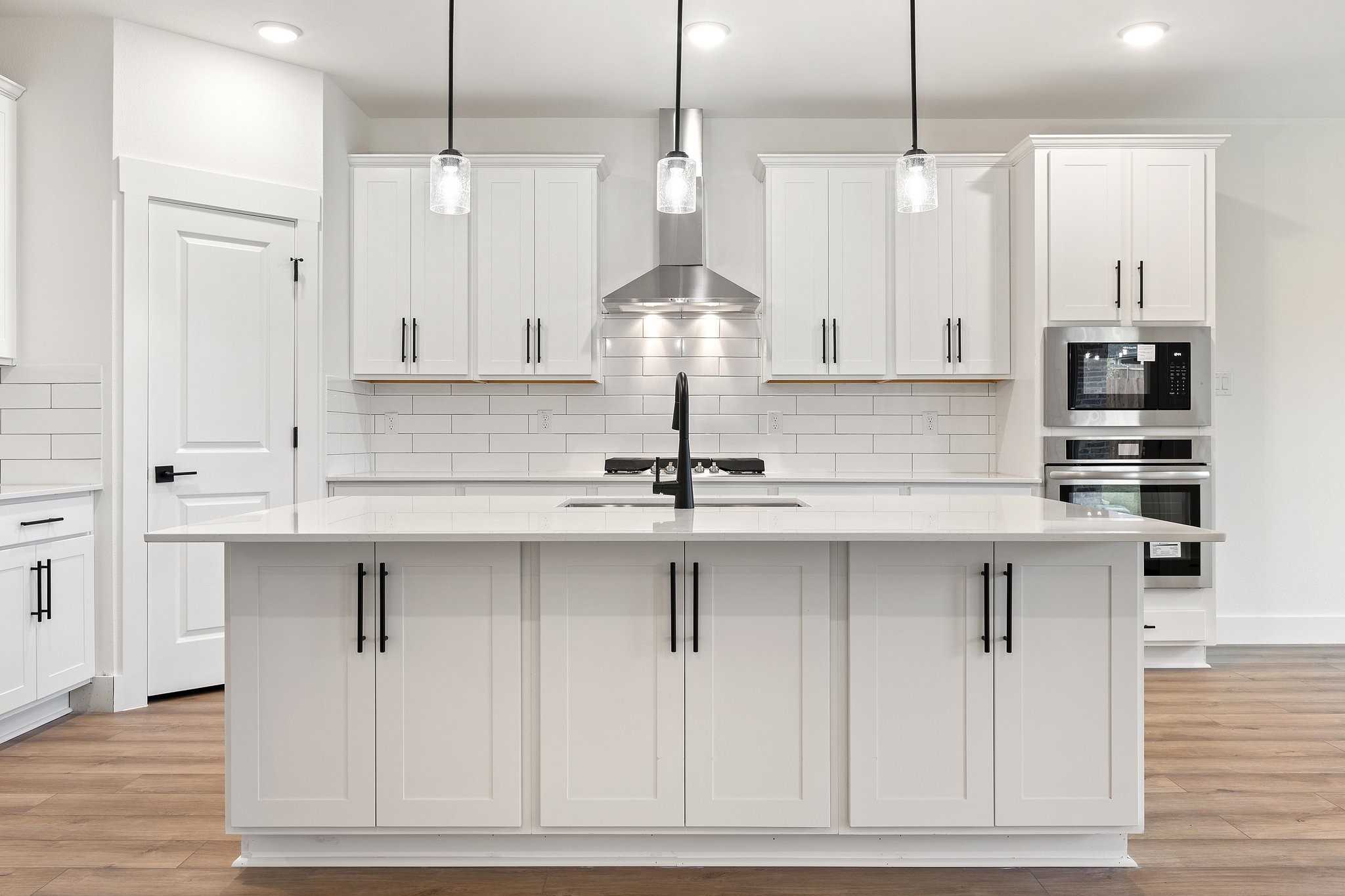 Modern white shaker kitchen with large island, subway tile backsplash, stainless appliances in Davidson Homes The Rockford C, Josephine, TX