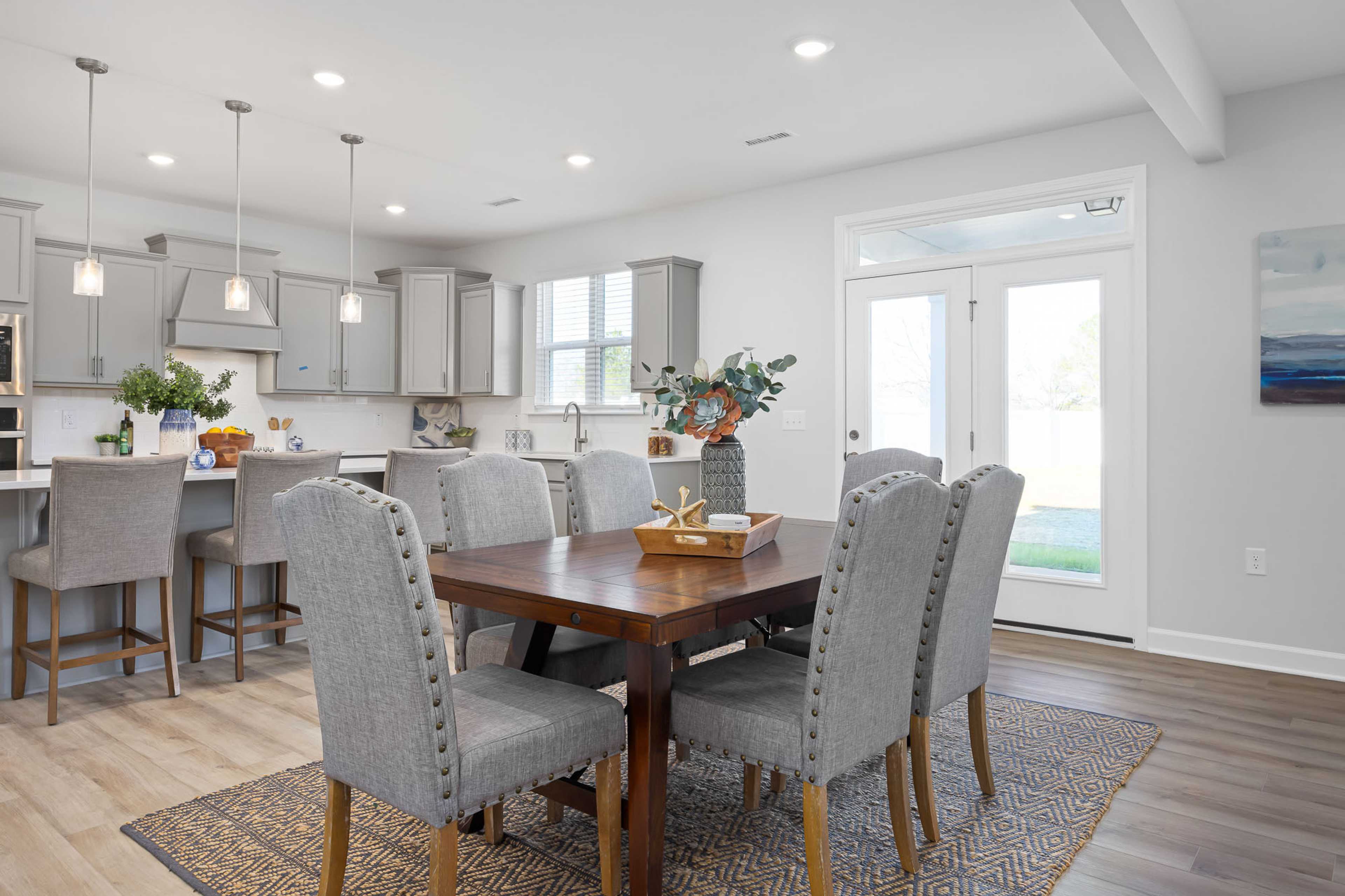 Modern open-concept kitchen dining area at Stagecoach Corner in Mebane NC with gray cabinets island bar and wooden table