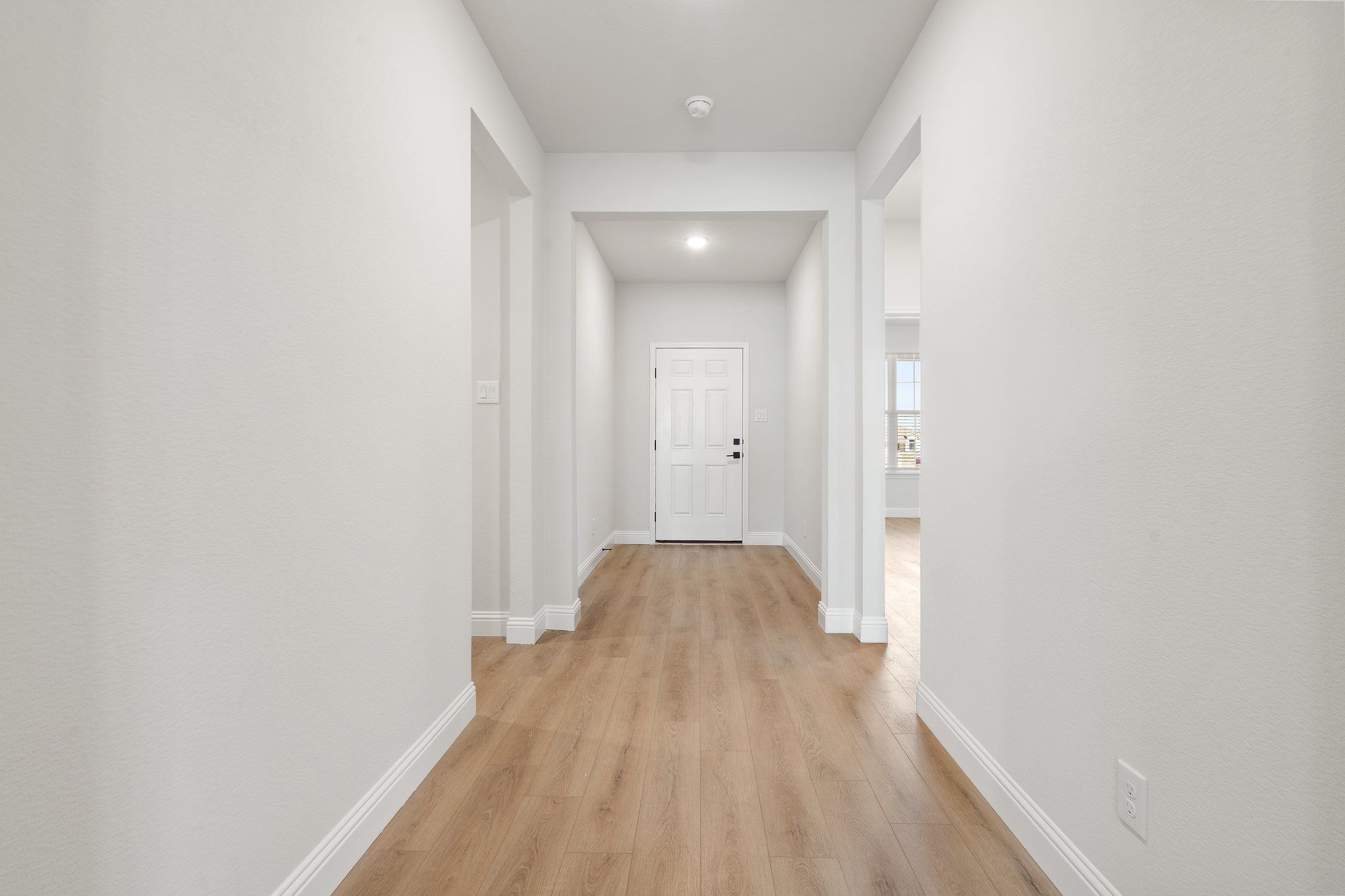 Bright, modern foyer in The Holly F home design by Davidson Homes featuring light wood flooring and crisp white walls.