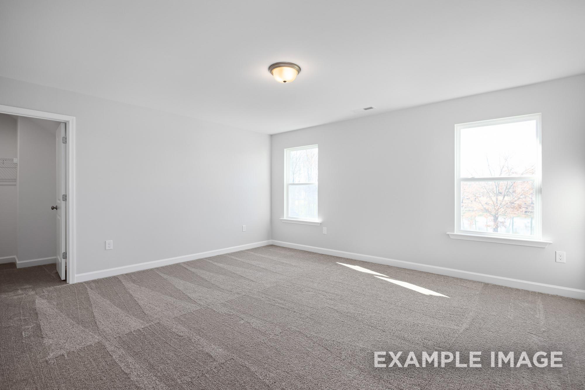 Spacious upper-floor bedroom in The Cypress B II with white walls, beige carpet, two sunny windows, and walk-in closet door