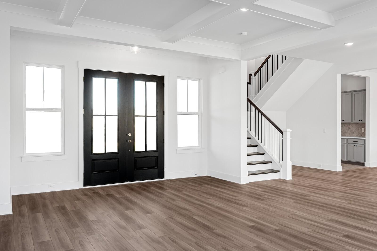 Grand entry foyer with hardwood floors, black double doors, and elegant wooden staircase in Davidson Homes The Alston A, Murfreesboro