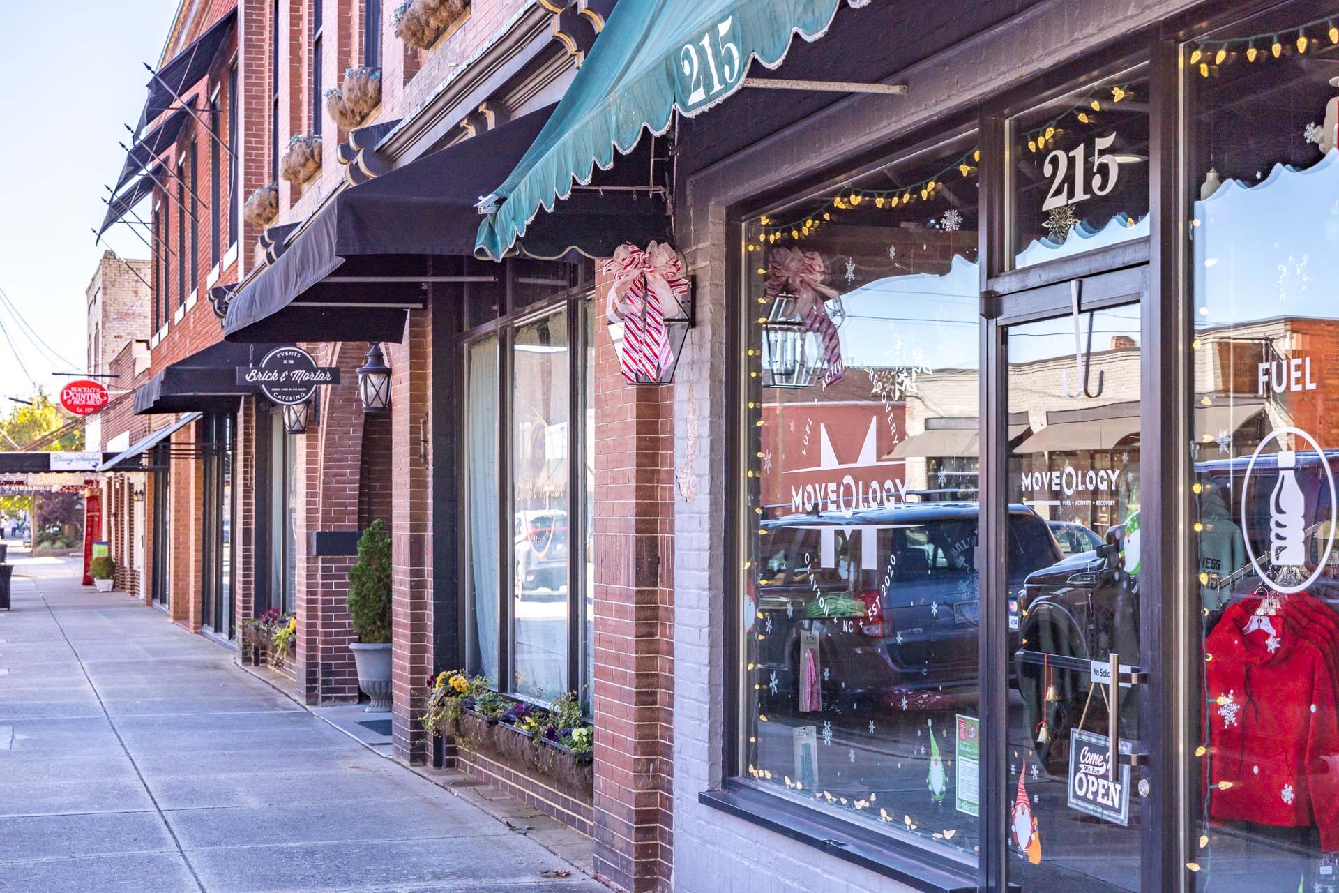 Festive brick storefronts with awnings, holiday lights, and red stockings on main street in Clayton, North Carolina near Sierra Heights
