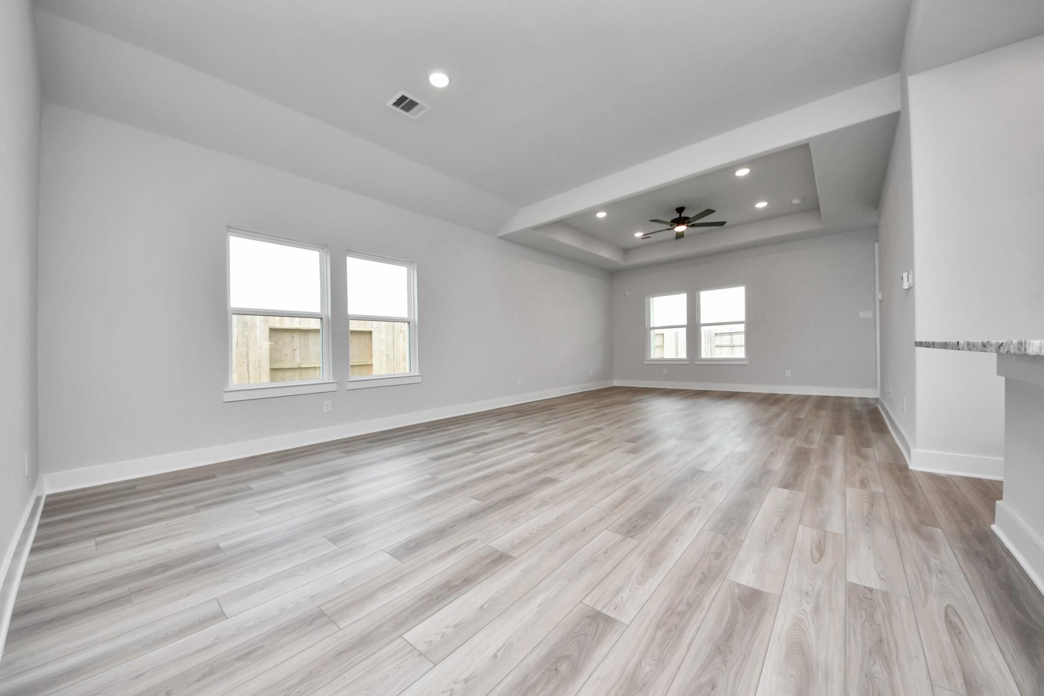 Spacious open-concept living room with tray ceiling in The Laguna C floor plan by Davidson Homes in Sunterra, Katy, Texas.