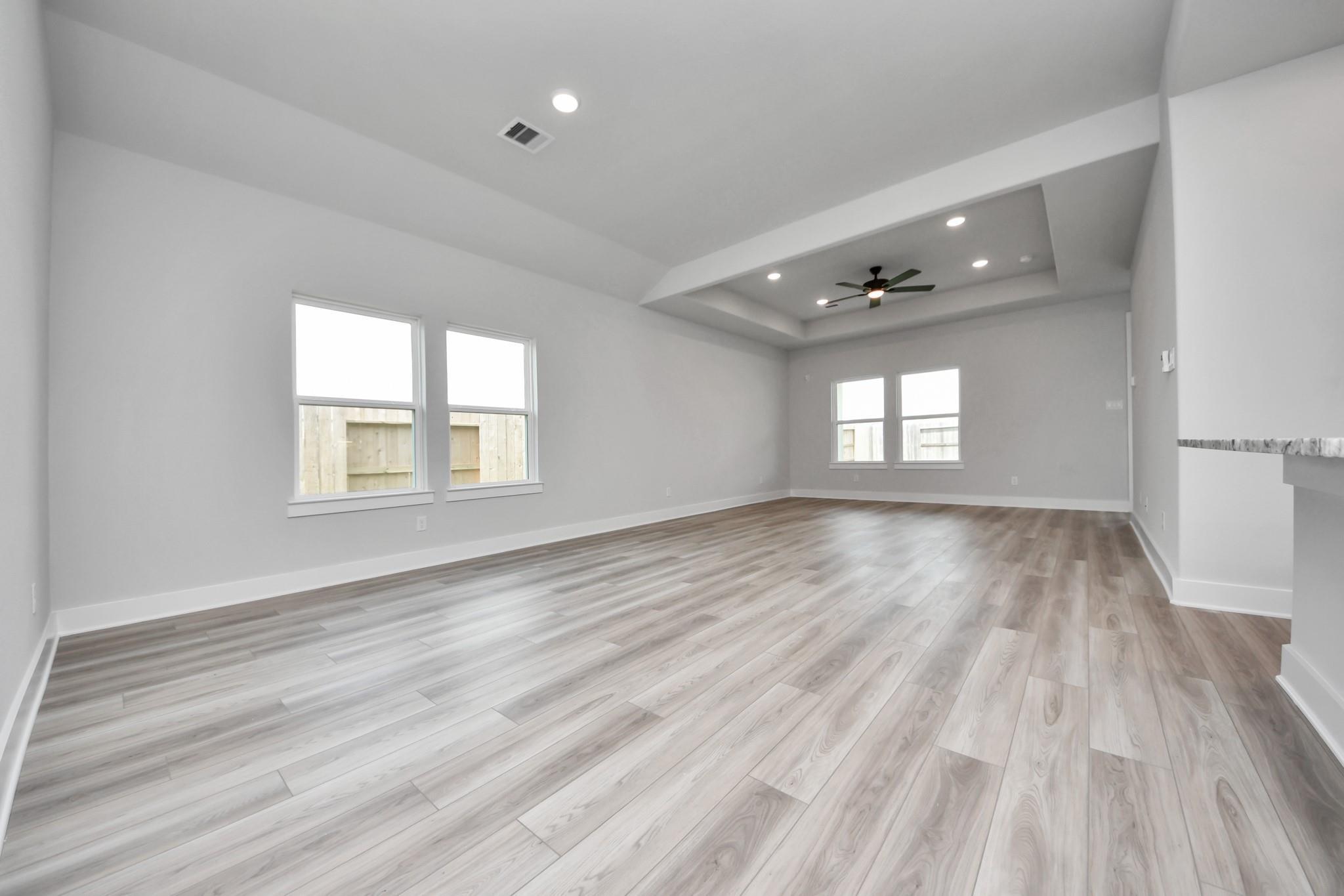 Spacious open-concept living room with tray ceiling in The Laguna C floor plan by Davidson Homes in Sunterra, Katy, Texas.