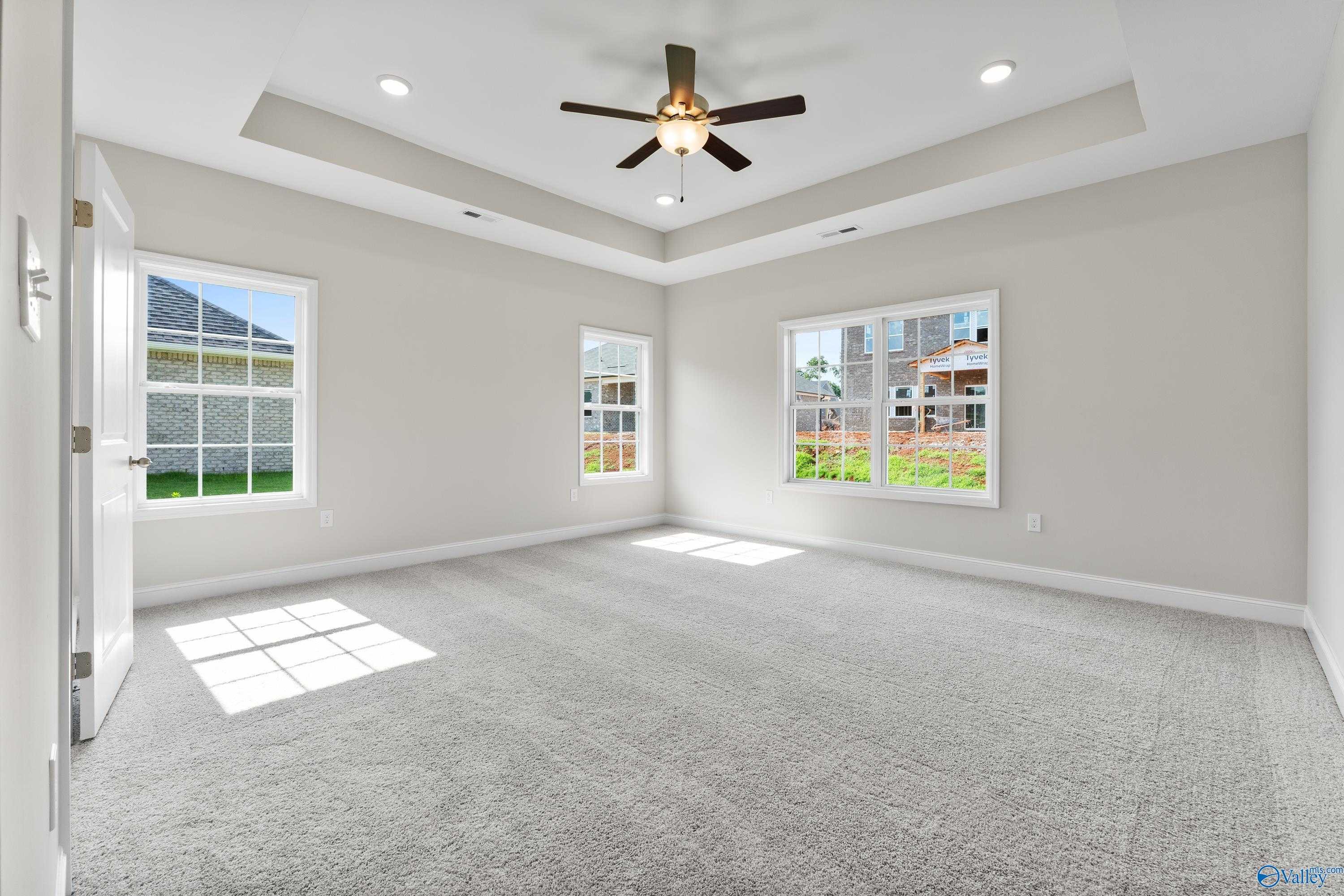 Bright bedroom with ceiling fan, large sunny windows, and plush gray carpet in Davidson Homes The Finleigh, Toney, Alabama