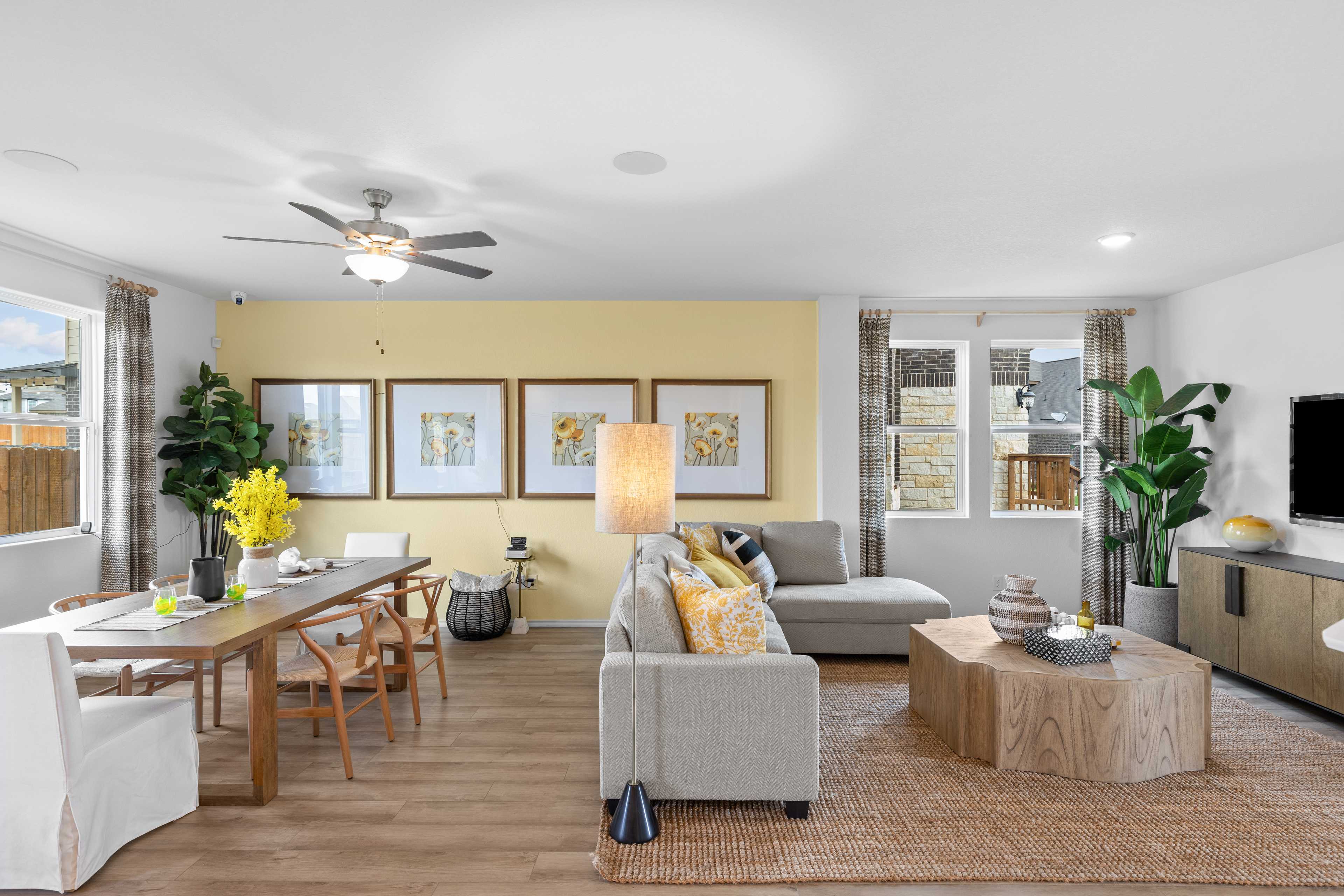 Spacious open-concept living and dining area at Horizon Pointe in Converse Texas with yellow accent wall, potted plants, beige sofa, and hardwood floors